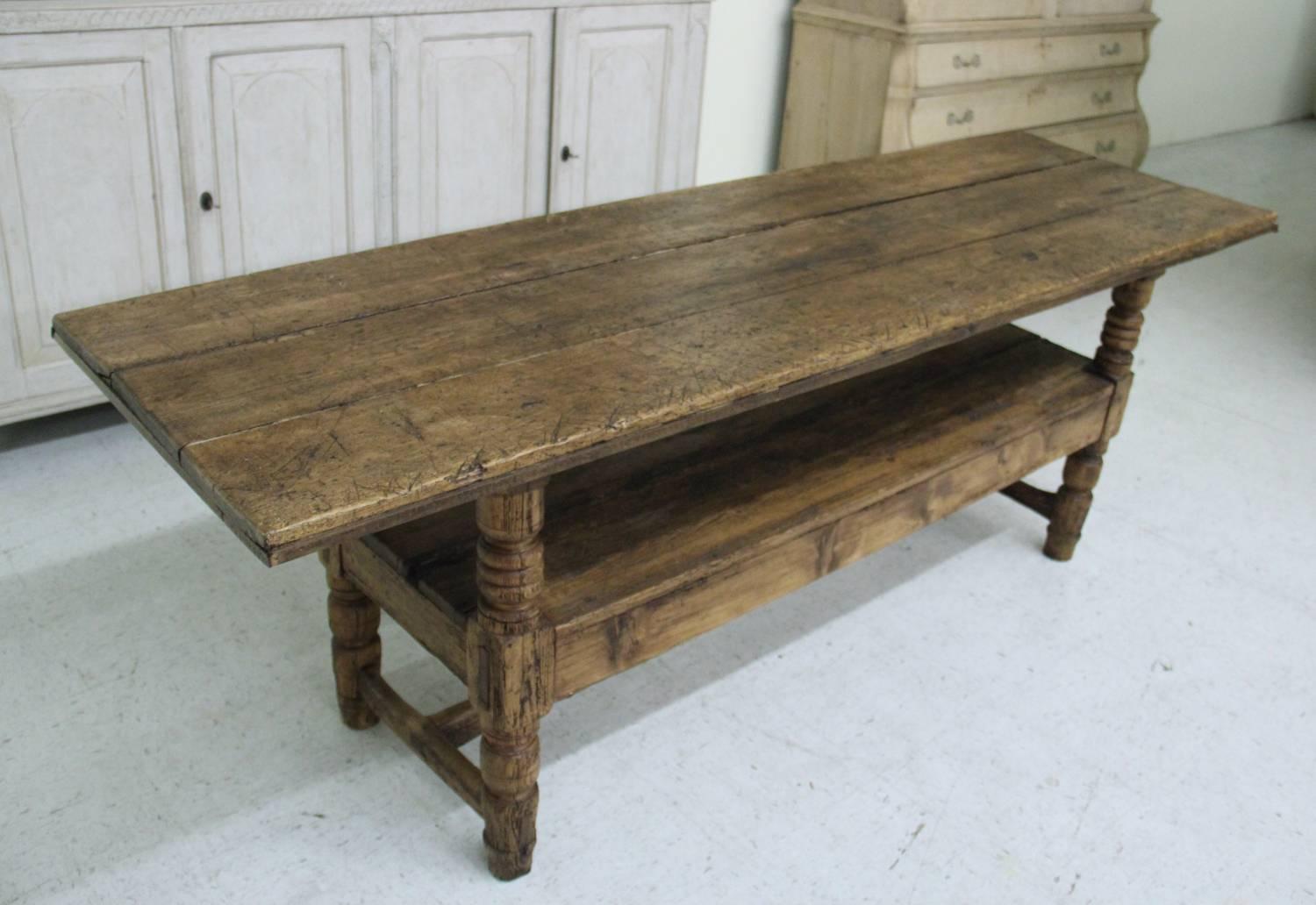 A 19th century Spanish Bishop's bench in the Provincial style that has been converted to a console table. The table has a plank top and turned legs with center stretcher below the lower shelf.