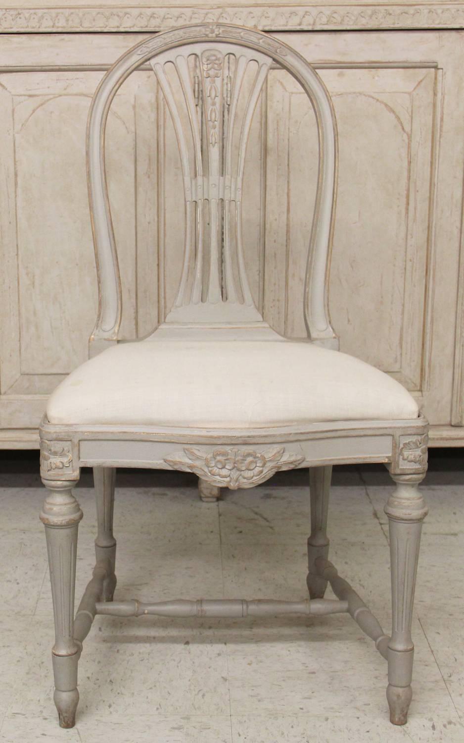 A set of six Swedish Gustavian Style painted wood side chairs with pierced slat and carved wheat sheaf back accented by carved rose detail, cross stretcher and slip seat cushions.

Seat size: 19.25