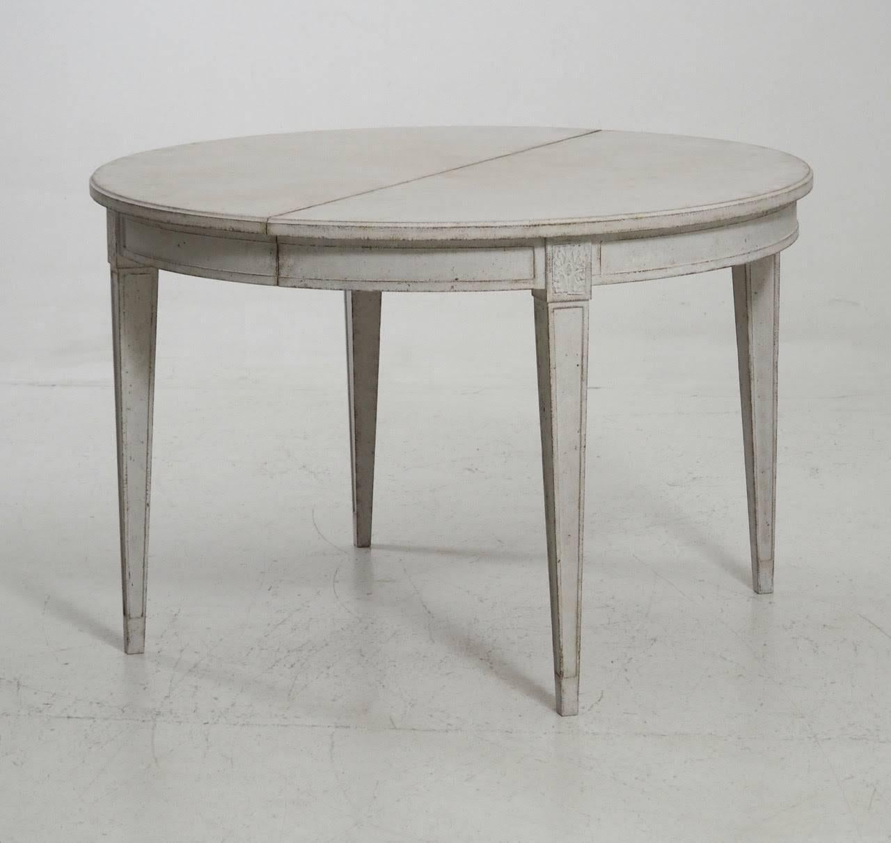 A stunning Swedish three-leaf extension dining table in the Gustavian style with square tapered legs accented by carved rosettes. A beautiful and versatile dining table that can extend with one, two or three leaves. 

Measures: Table diameter
