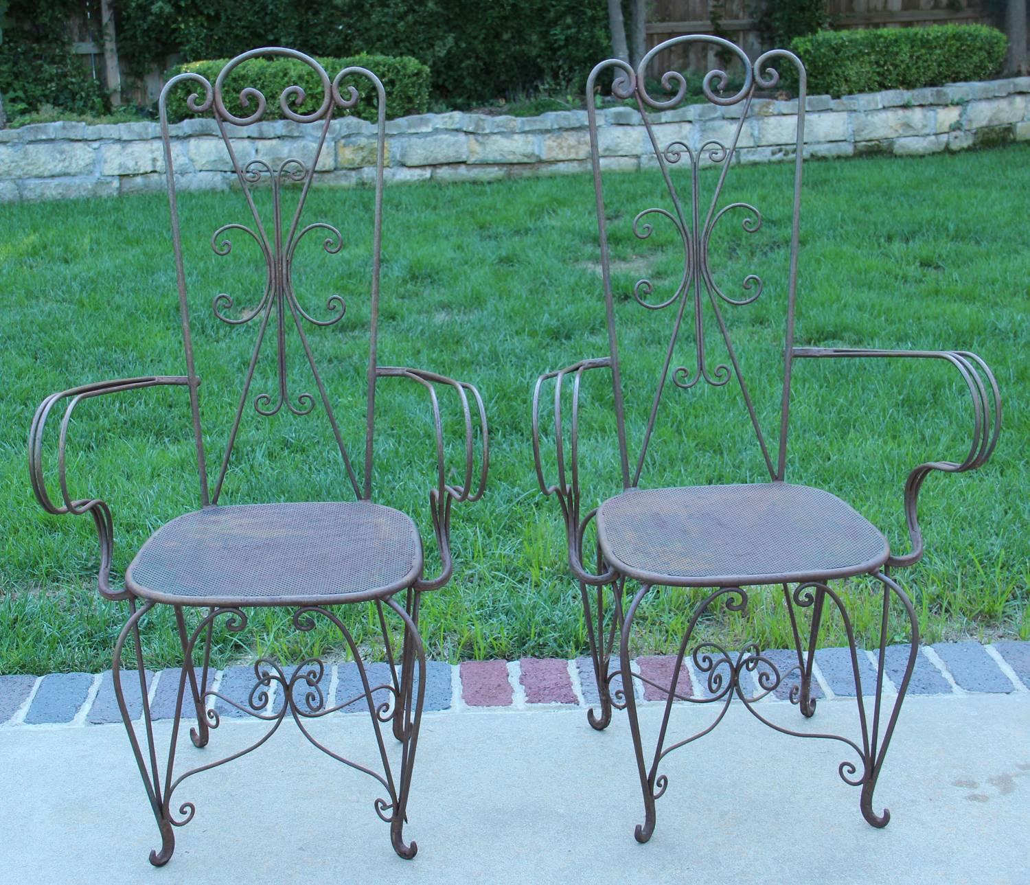 A charming pair of iron chairs with curlicue design on backs. The square seats have a mesh pattern and are raised on cabriole legs, ending in tiny scrolled feet. Found in Paris.