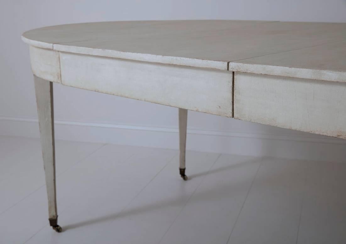 A rare Swedish Gustavian period four-leaf extension table from the 19th century with both original pairs of center support legs and original oak extension mechanism, circa 1810. The table is a light gray and has its original brass wheels. The center