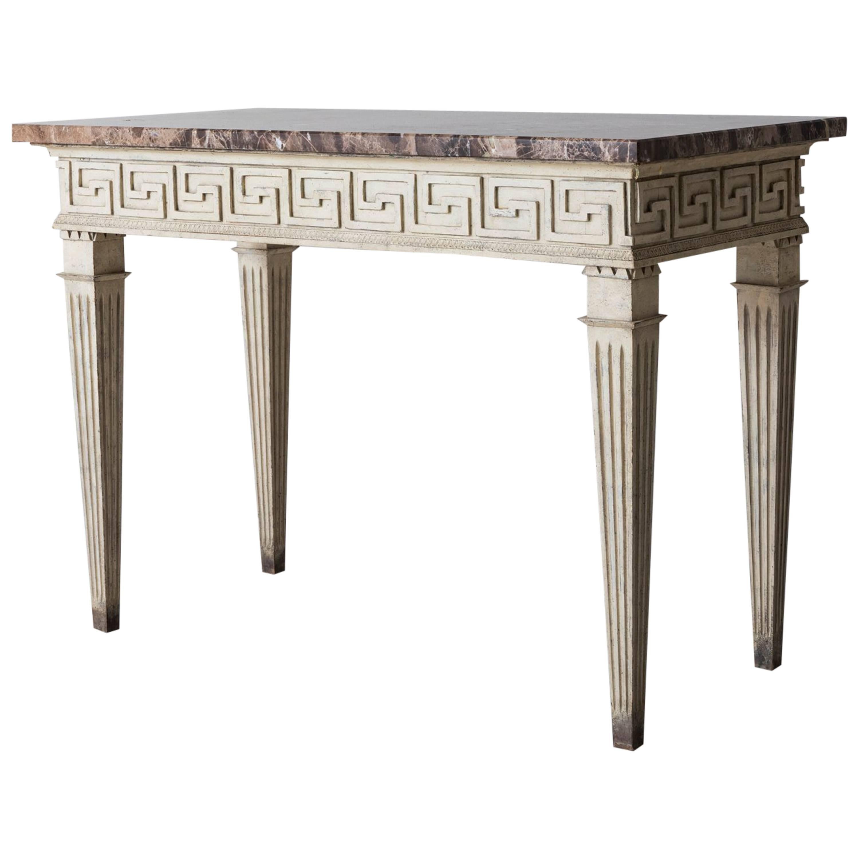 A French original paint console table in the Louis XVI style with original marble top. The apron is finished on all four sides and features a carved neoclassical Greek key design and rests upon square, tapered and fluted legs. The apron height is