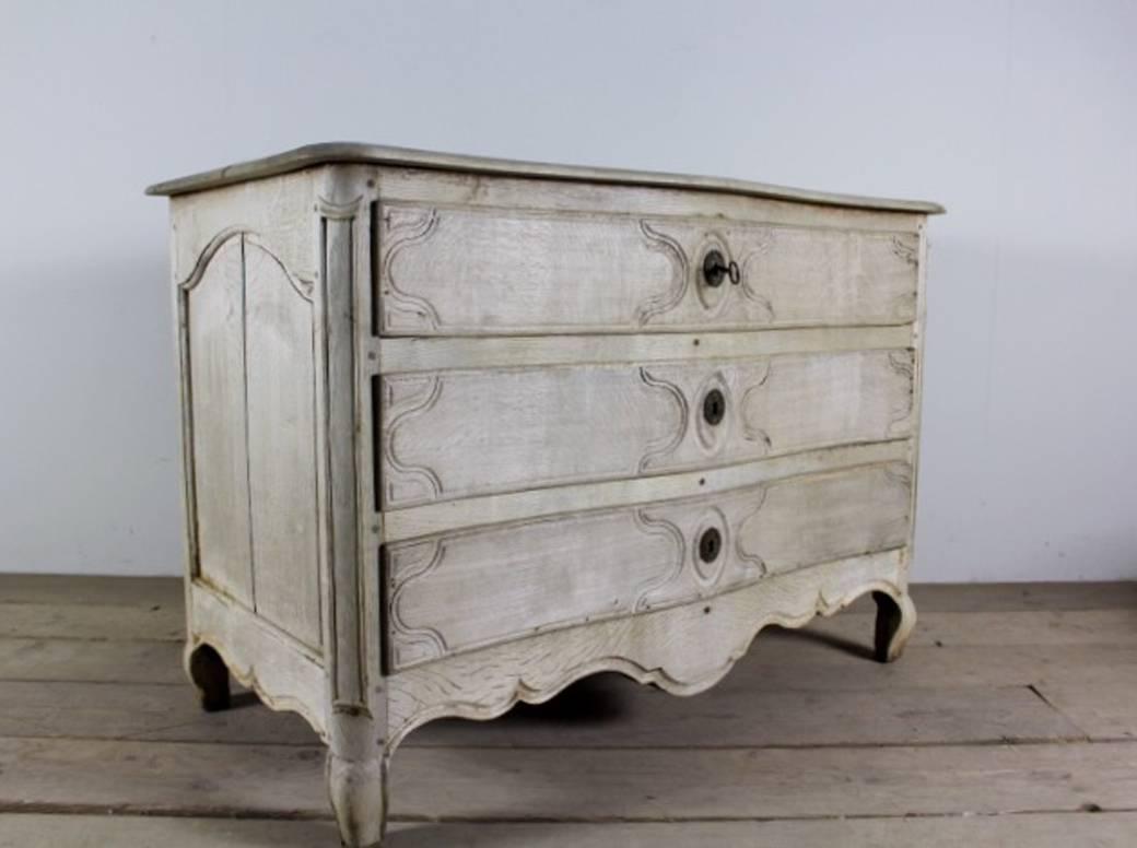 A French Louis XV style bleached oak chest with a serpentine front, shaped top, original locks, scalloped apron, and cabriole legs.