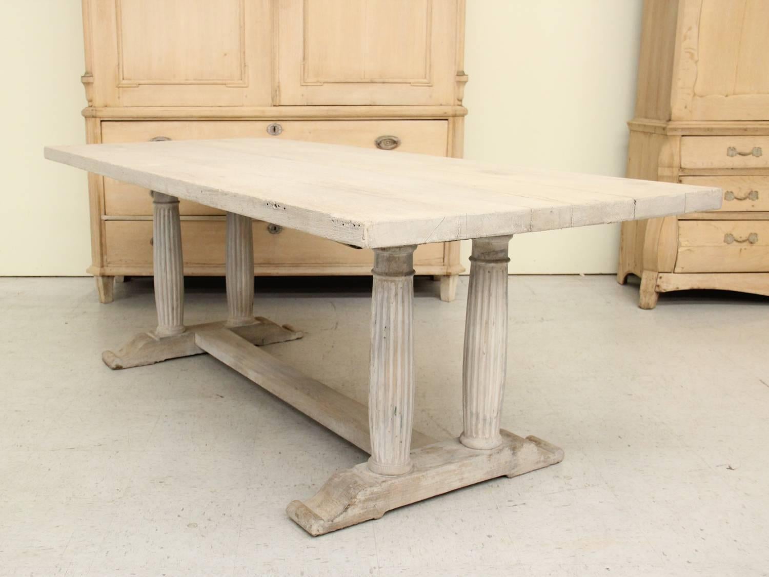 A French oak dining table from the 19th century with an aged white painted patina. This beautiful table has a plank top; reeded, gun barrel legs; and a sled base with stretcher.