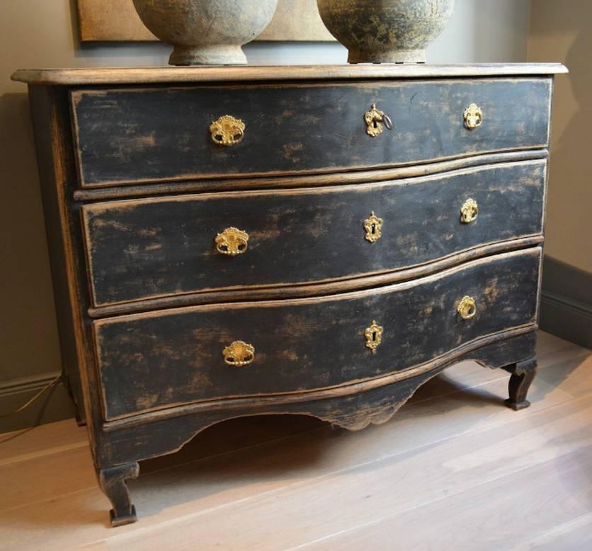 An exceptional 18th century Swedish commode from the Rococo period in old black paint with original locks and gilded brass hardware, dated on the back 1757. This commode has a serpentine front and shaped apron to the front and sides, and is raised