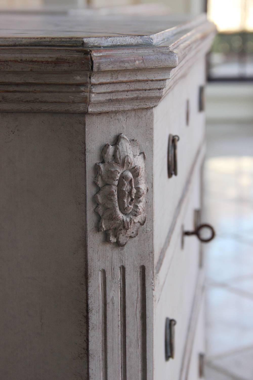 A beautiful neoclassical pair of Swedish Gustavian style painted chests with hand-painted marbleized tops and tapered legs. Each chest has three drawers, brass hardware and original locks. The corner posts are canted and fluted with carved rosettes