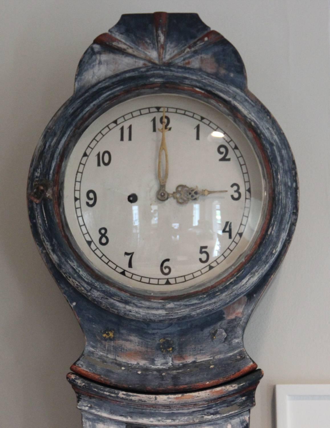 A Swedish tall case clock from the Gustavian period in the Classic Mora form. This charming clock has retained its original blue paint surface and hand-painted floral and leaf motif. Original glass, face, clockworks, pendulum and weights. This clock