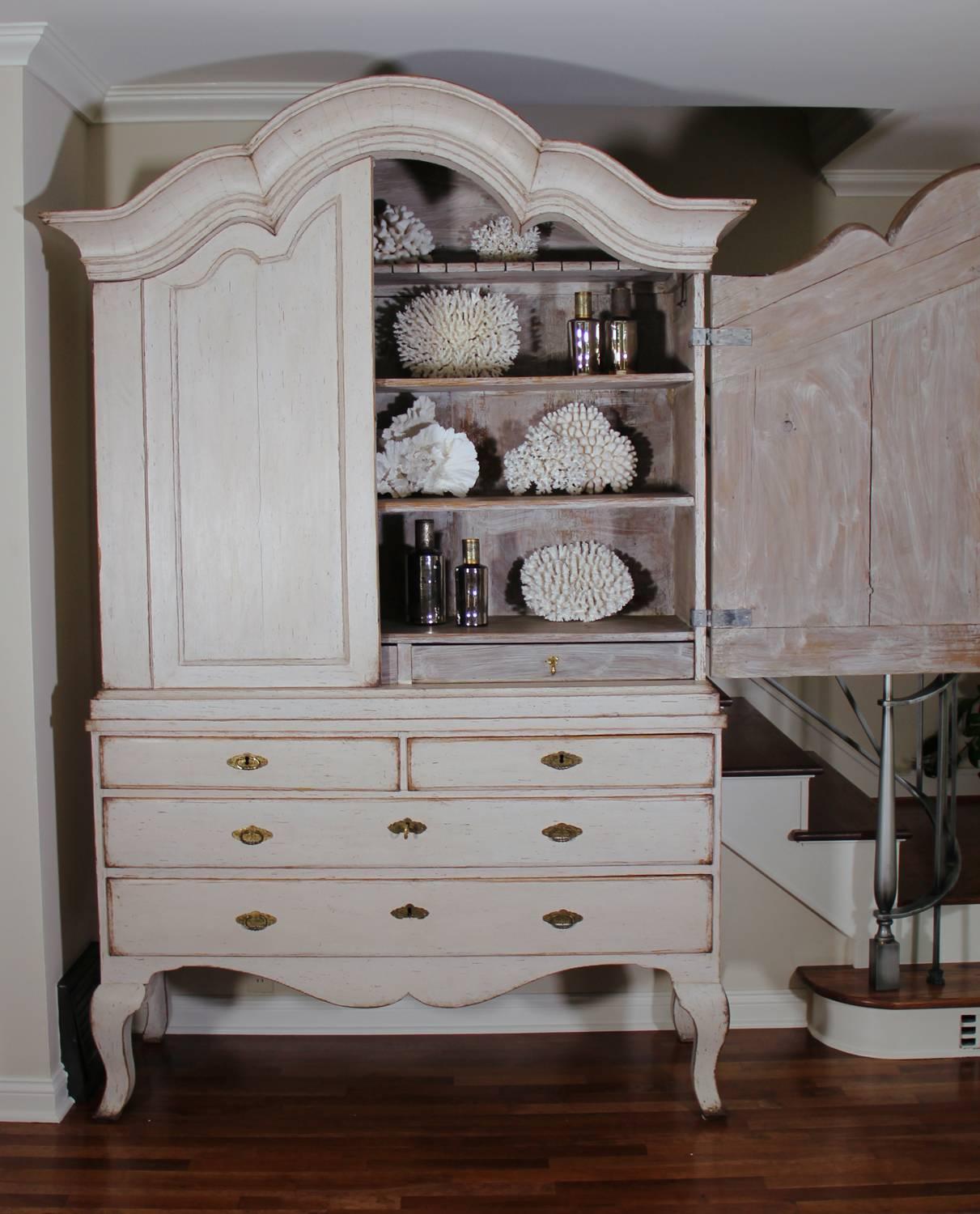 A 18th century three-part Swedish linen press or armoire from the Rococo period with original brass hardware, locks, and keys. This cabinet is beautifully proportioned with a gracefully arched pediment cornice and elongated cabriole legs. The