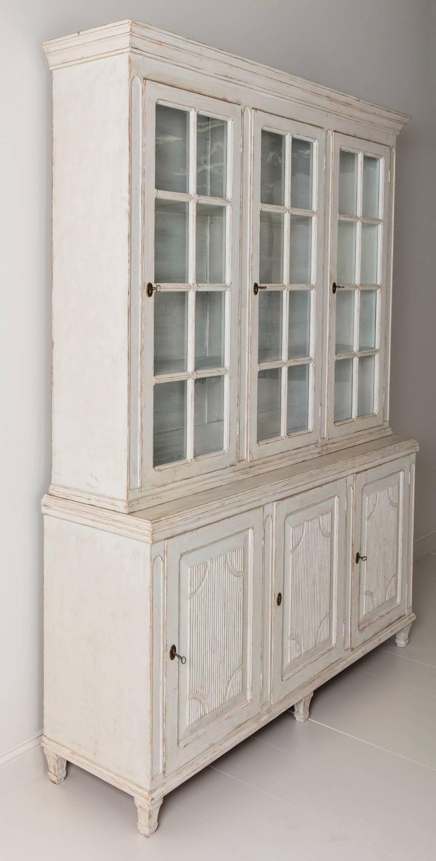  A beautiful Swedish Gustavian style three-door painted vitrine cabinet from the 19th century.  The paint is later, although it reads like original paint.  The finish is very chalky and there is natural wood showing through in areas.  This bookcase