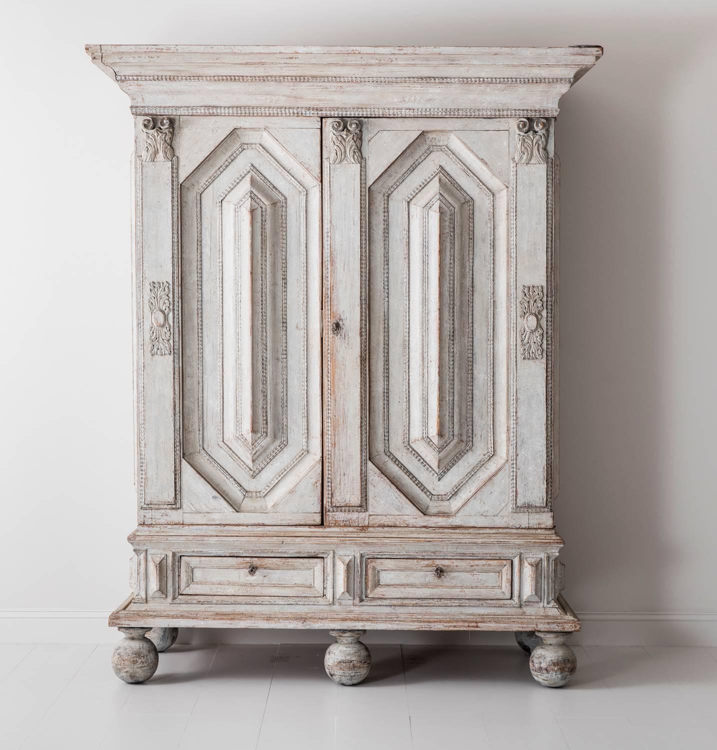 A monumental and richly carved Swedish armoire or linen press cabinet from the Baroque period with handsome ball feet, circa 1750. The large doors sit above a pair of drawers and open to reveal four internal shelves. This is a rare piece with plenty