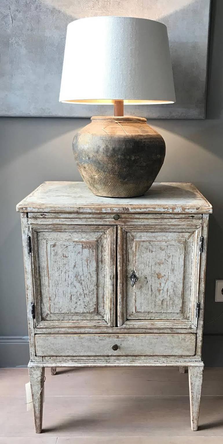 A Swedish Gustavian nightstand from the 18th century. This charming piece has a pull out top shelf and a bottom drawer below cabinet doors that open to an internal shelf, circa 1780.
