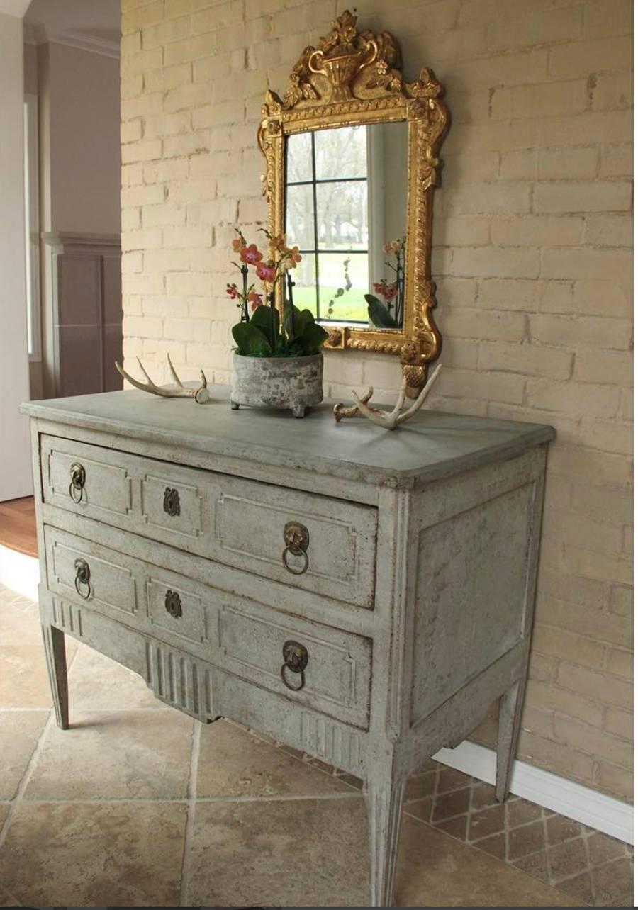 A rare Italian commode from the neoclassical period in old, time-worn blue grey paint with original locks and brass lion head hardware. This beautiful chest has canted and fluted sides, fluted detail on the apron, and rests upon tapered and fluted