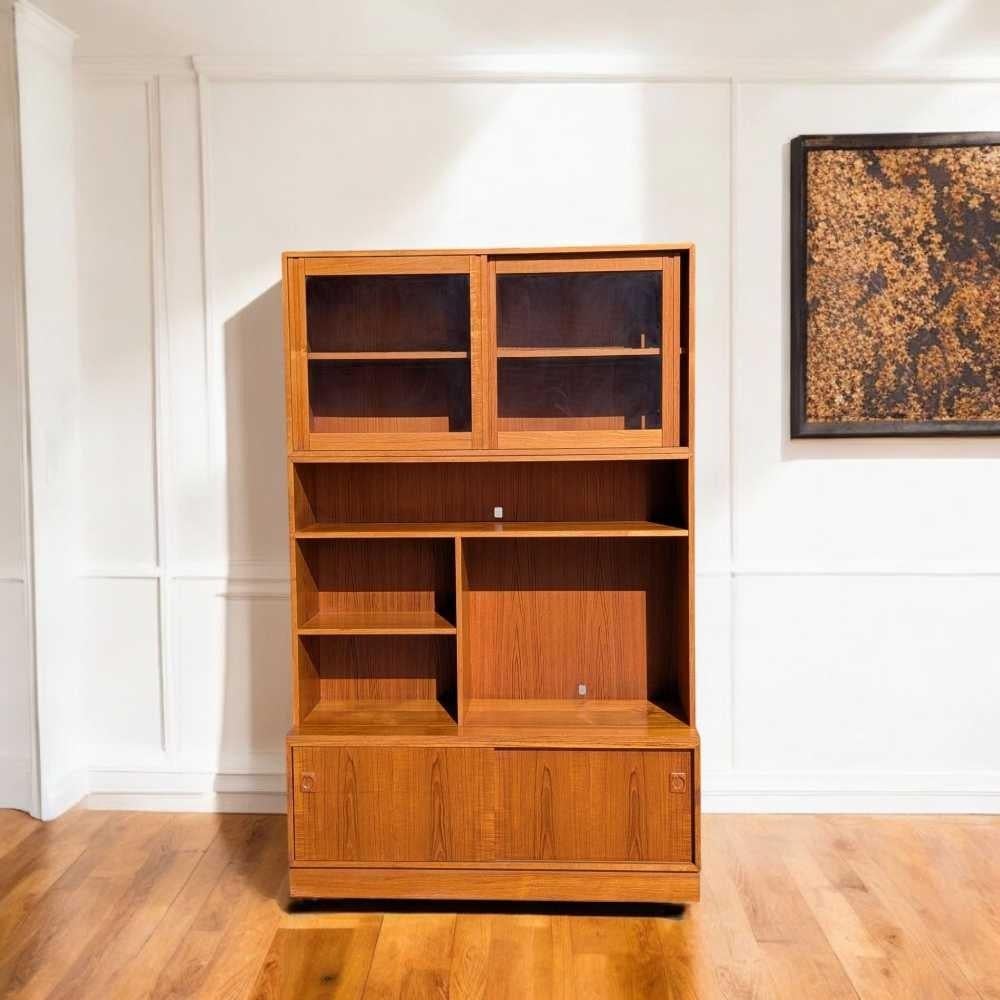 Un'originale libreria e vetrina danese della tradizione moderna di metà secolo, realizzata in calda impiallacciatura di teak e caratterizzata da una combinazione di scaffali aperti e contenitori chiusi. Il mobile superiore offre spazio ideale per