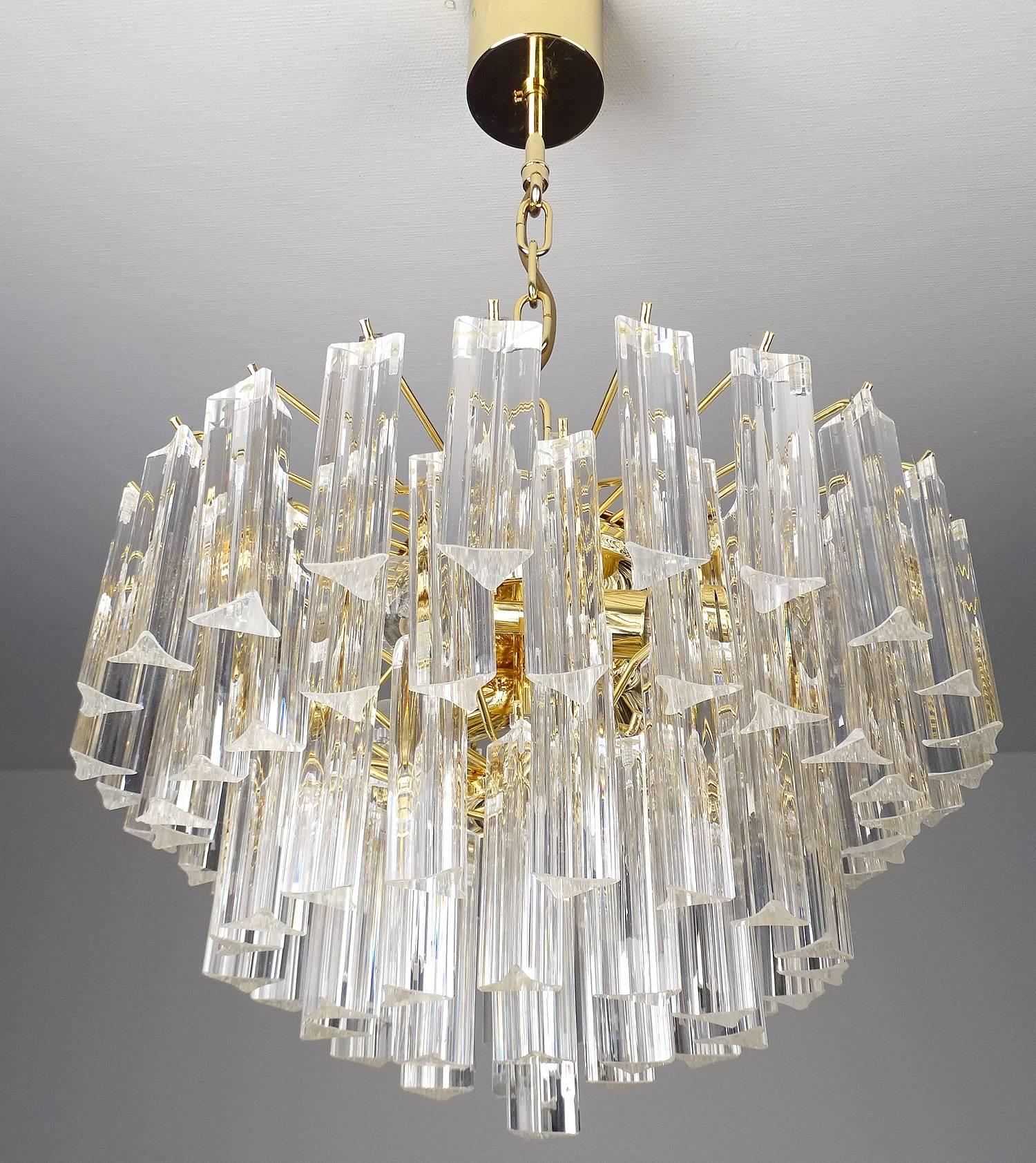 This Mid-Century Modernist chandelier by Venini features individually handmade Murano glass triedre prisms hung in six tiers  individually hung from its gilded frame, hung in a descending form giving it a cascading effect and overall circular form