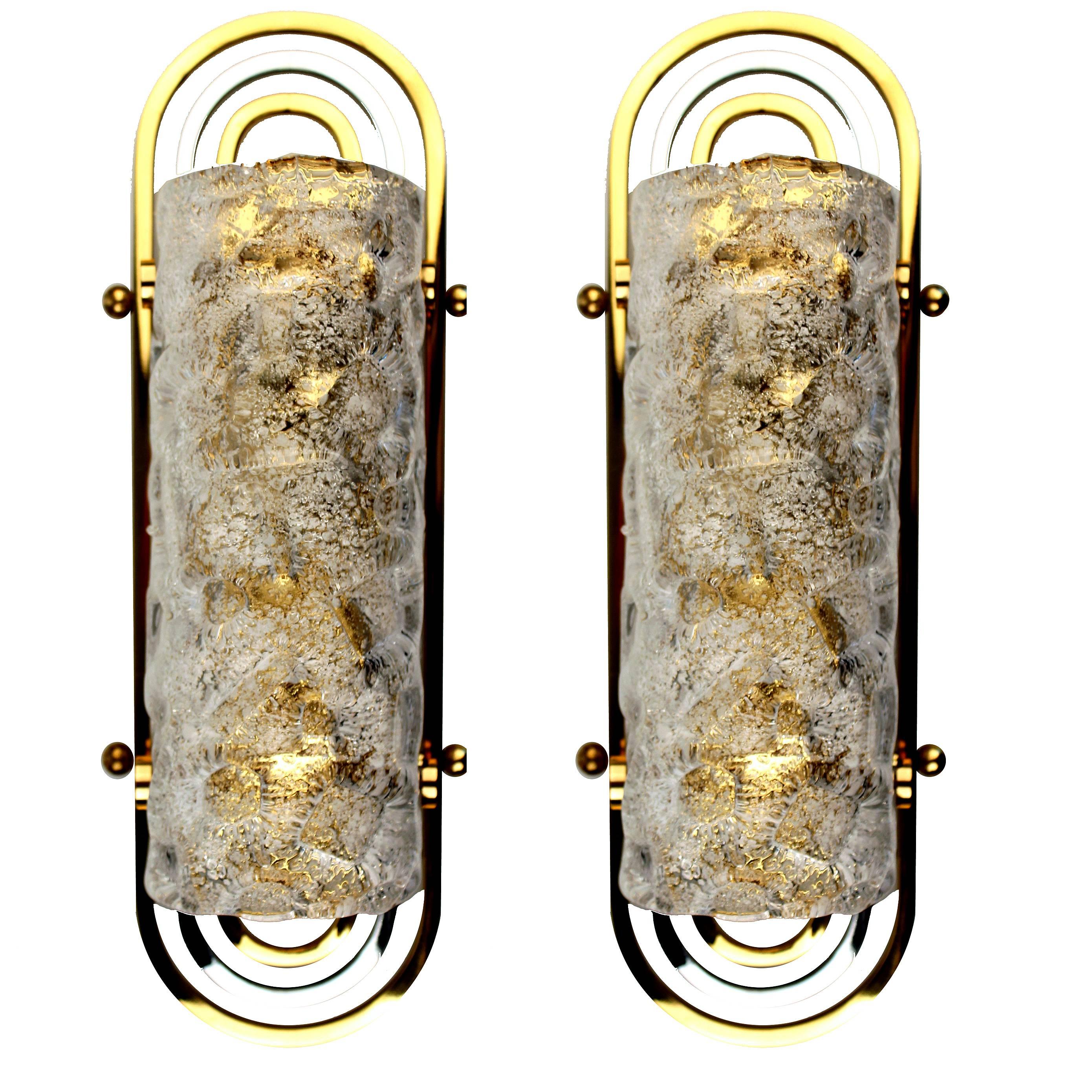 Pair of Schro¨der sconces, half cylindrical murano glass shades set on a triple loop chrome and brass frame.

One candelabra size bulb up to 60 watts each - LED compatible - run on voltage from 110 till 240 volts.

With the 1960s came the