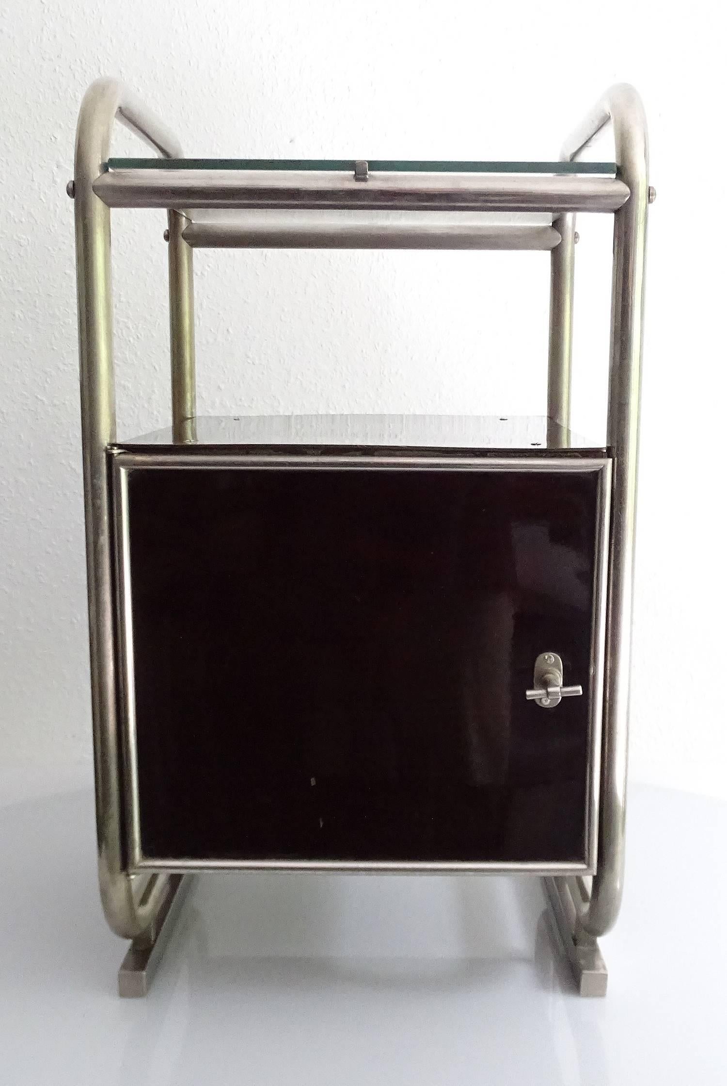 Extremely rare pair of original 1930s Bauhaus design bedside tables / nightstands, tubular construction on skid base with glass plate, core metal storage box coated with bakelite plates. This is extremely unusual as these were usually made out of