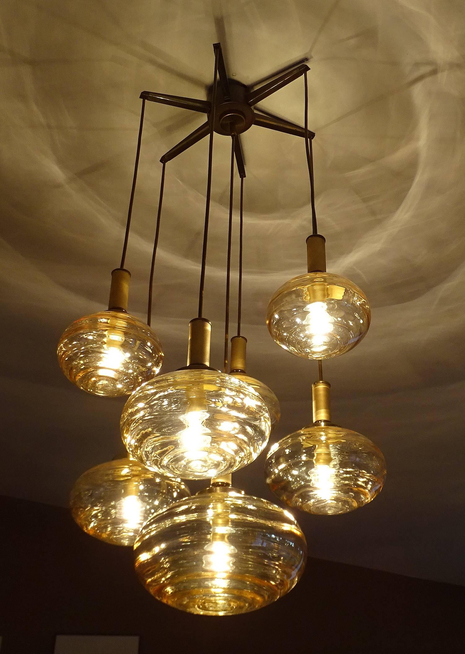 Multi-tier chandelier by Limburg featuring 7 blown glass globes with overlayered swirls, as each of the globes were handcrafted, their surface structure can differ, great lighting and shadows effect when lit up.
40.16 in. / 102 cm H (cables can be