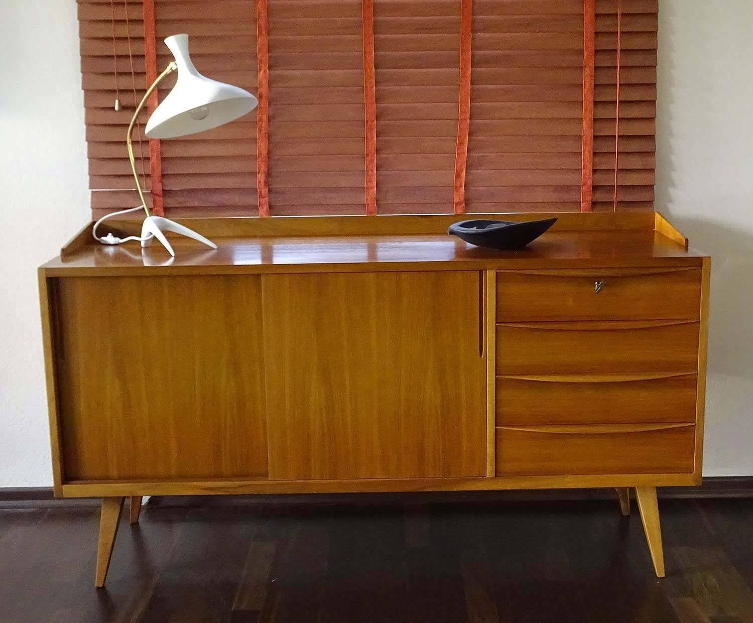 Midcentury Danish modern style sideboard manufactured by the Deutsche Werkstätten, series 802, 1956, design by architect Franz Ehrlich. This sideboard features three drawers and two sliding doors, large compartment with one large shelf.
30.51 in. H