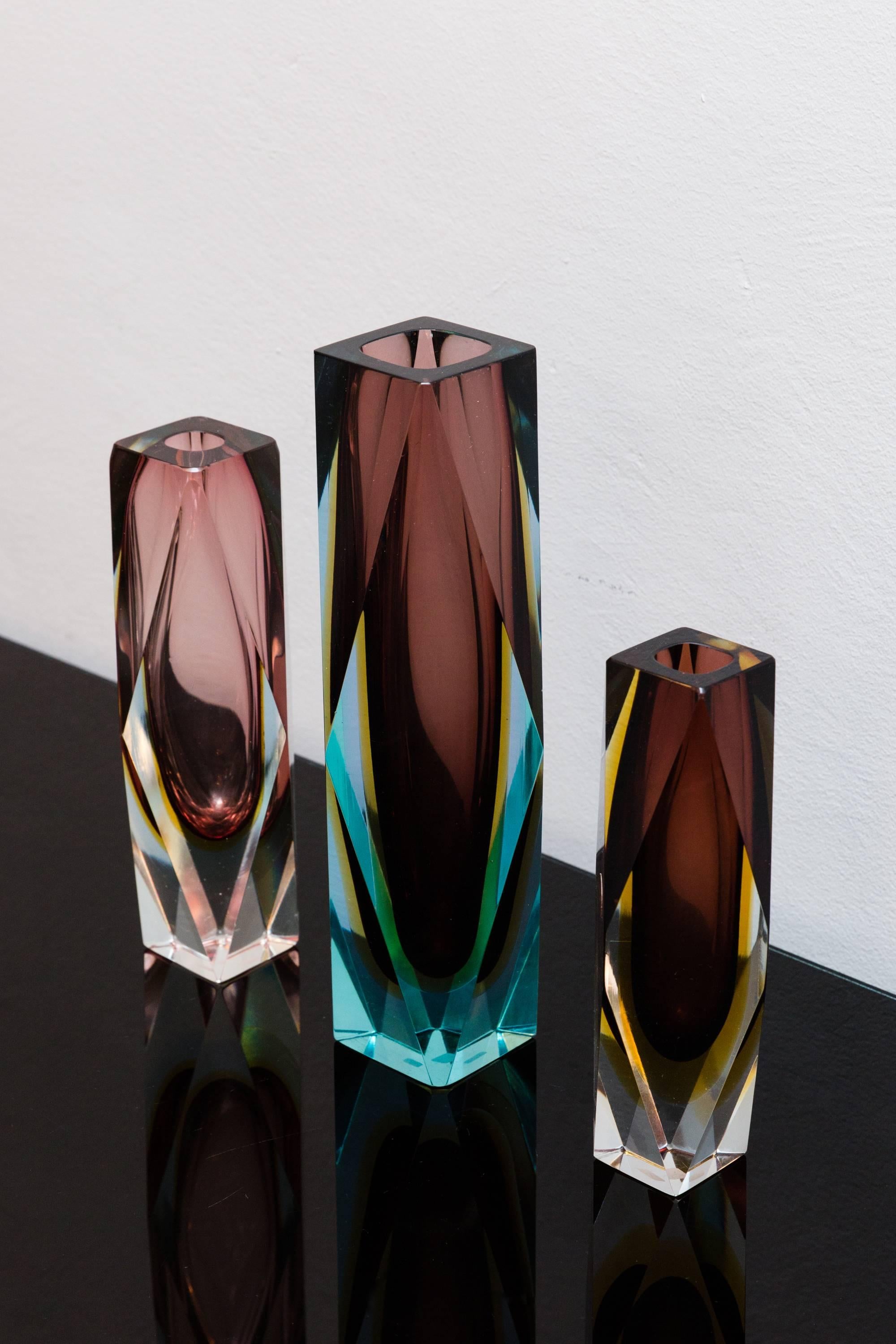 Beautiful multi-color set of three faceted / block vases, Italy, circa 1960, Prod. Sommerso, Murano attributed to Alessandro Mandruzzato. Color purple, amber-yellow, turquoise, cased into clear glass. Some Vases signed with the original sticker.