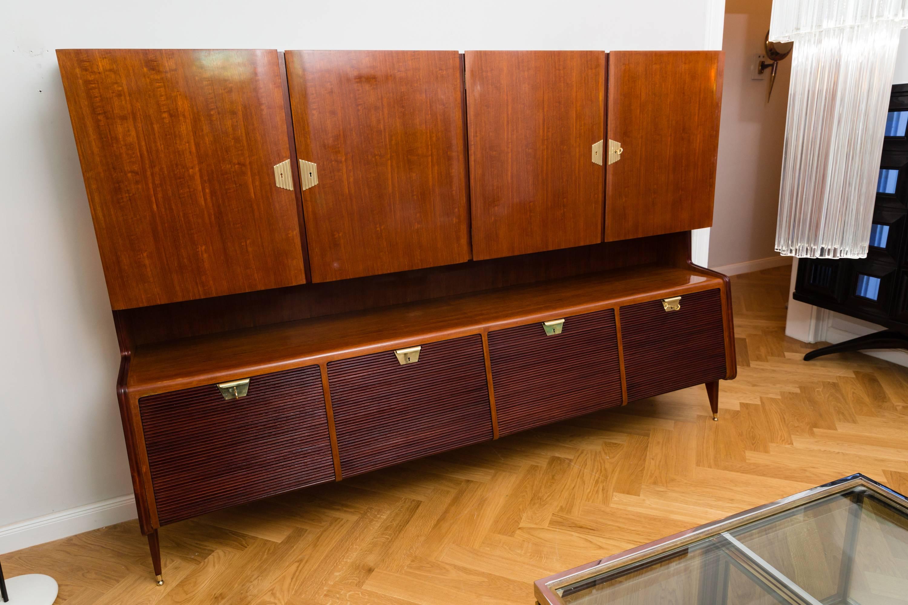 Rare large cabinet attributed to Guglielmo Ulrich, Italy circa 1950, walnut wood, walnut veneer, brass elements, four folding doors on the base, four doors on the front, brass handles, brass keys, two shelves, organic shaped side panels with brass