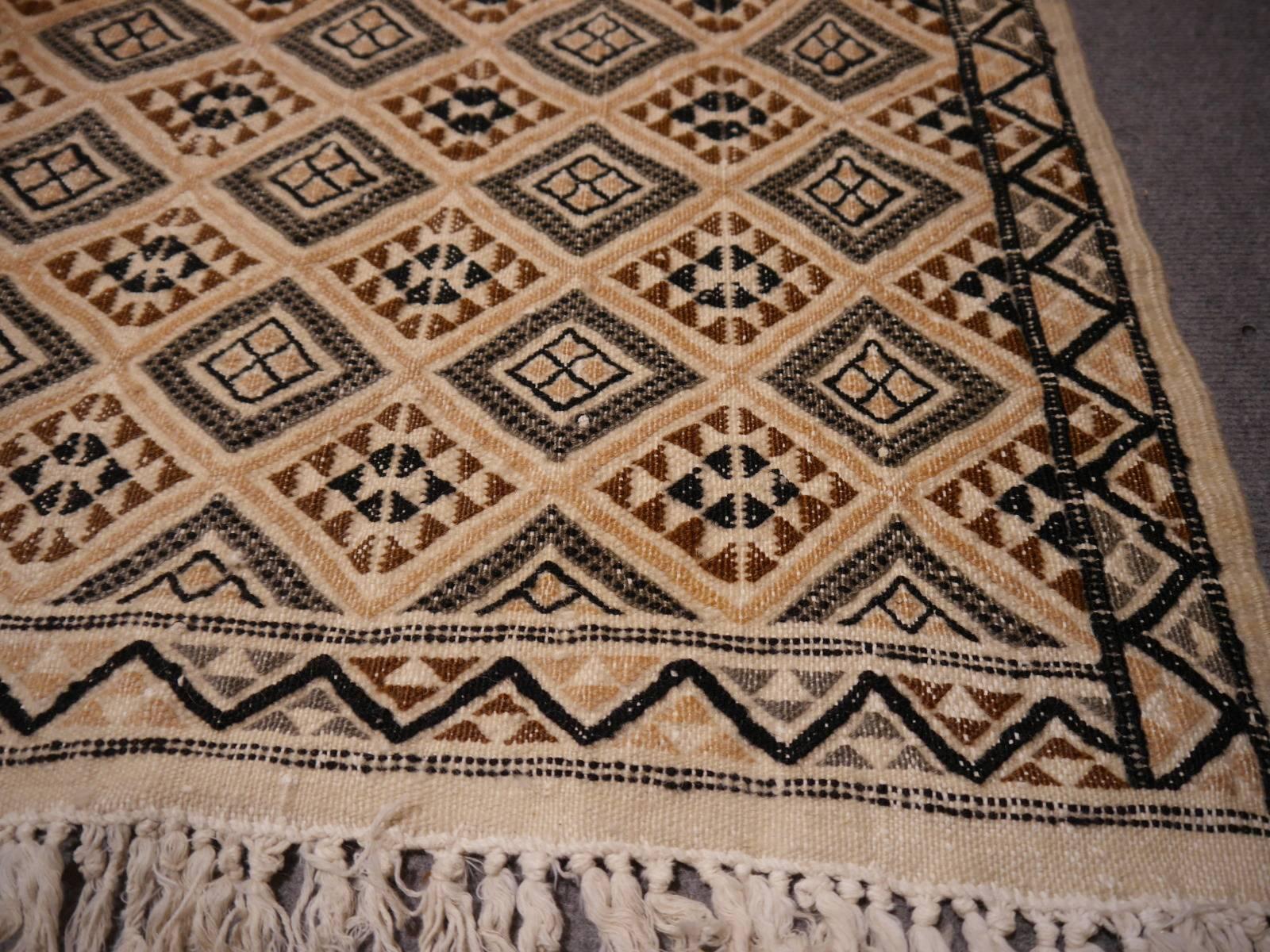 Beautiful handwoven and hand embroidered Berber Kilim. Very good condition and great colors. Warp is cotton, weft and embroidery is made of wool.

The colors of this stunning rug are beige, brown and dark brown - almost black.
The condition is very