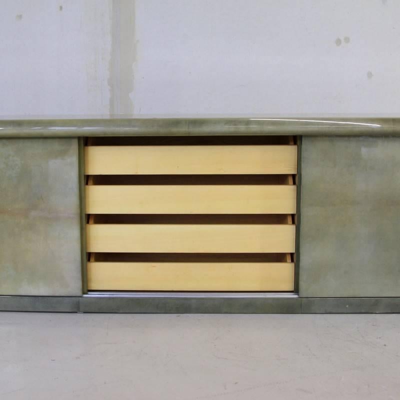 Large sideboard designed by Aldo Tura, Italy, 1960s.

Sideboard with three sliding doors, two glass shelves and five drawers. The sideboard is covered in light green lacquered parchment. With Aldo Tura label.