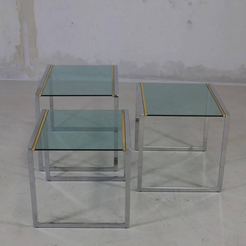 Nest of three tables, France, 1970s.

Chrome-plated frame with green glass tops and brass detail.