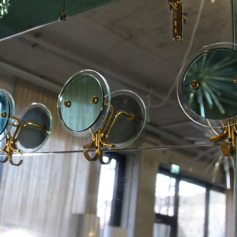 Large Italian floor mirror, 1950s.

Mirror with framed green mirrored glass panels and four glass and brass hooks.

Brass details.
Condition: 

Good condition, the mirror glass is partially slightly blind.
 