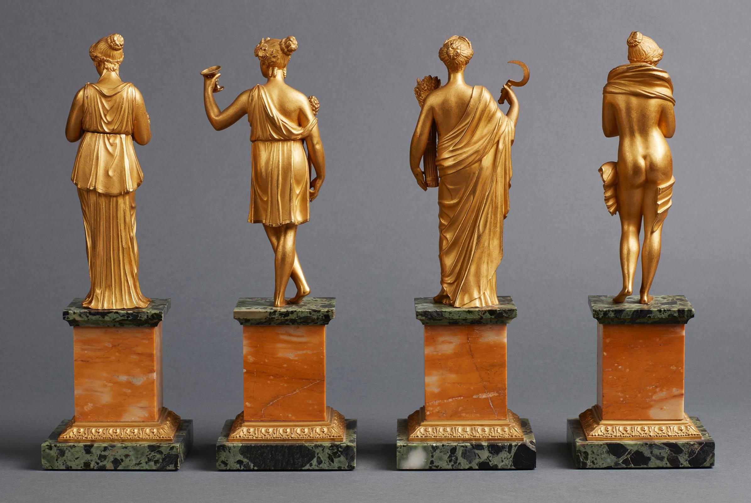 A rare and very decorative set of four gilt bronze figurines of ancient goddesses emblematic of the four seasons. Each figure standing on a square pedestal made of green and yellow marble with a central ormolu floral ornament and an accanthus leave