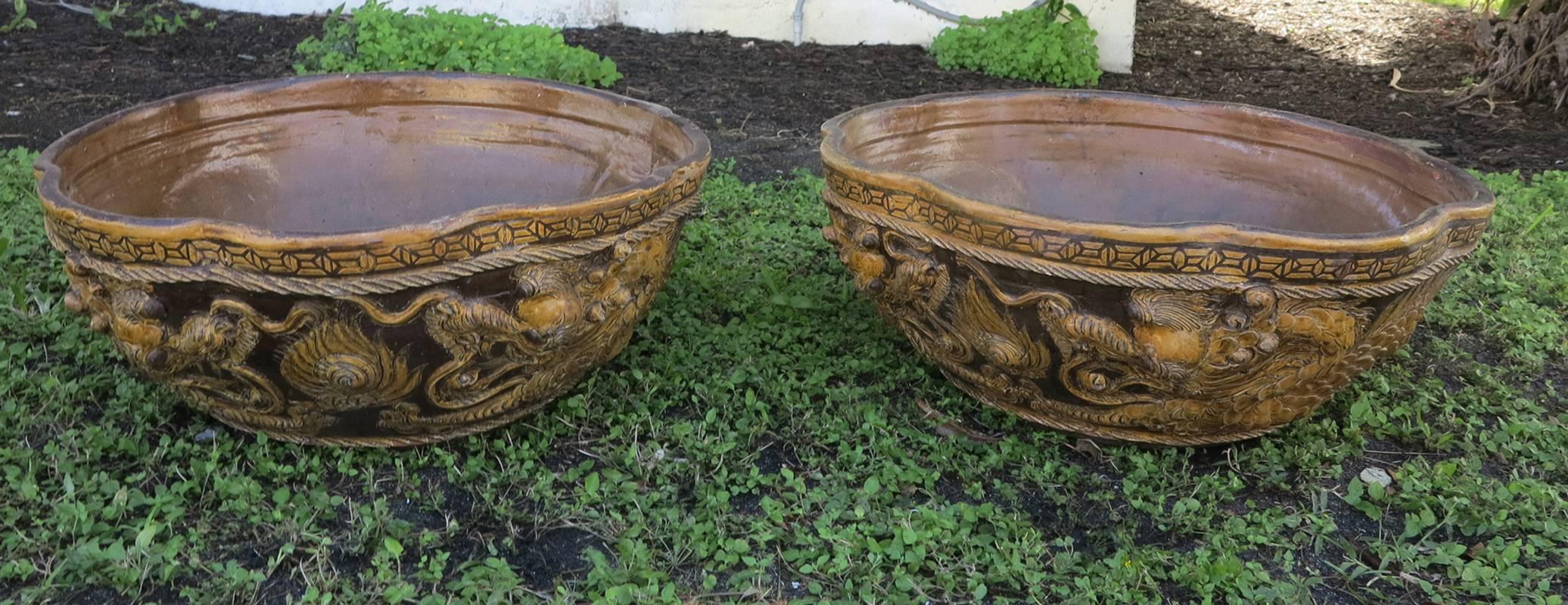 Pair of large antique terracotta planters 19th century probably from England with Chinese styling. Scalloped edges approximately 26 inch diameter. Some minor glaze loses.