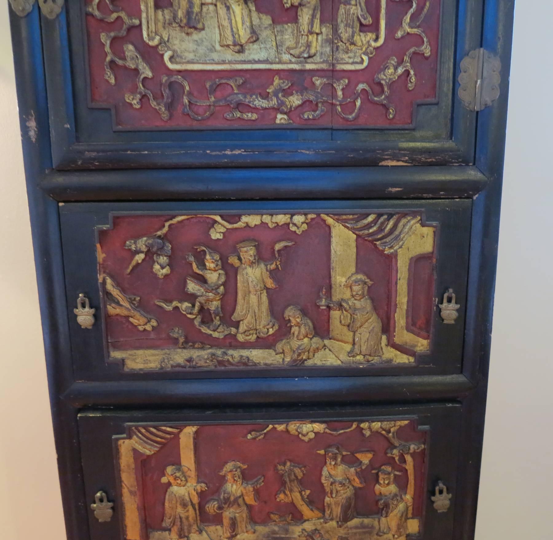Chinese cabinet 19th century polychromed giltwood panels. Carved panels some pierced carved. Original finish with brass fittings.