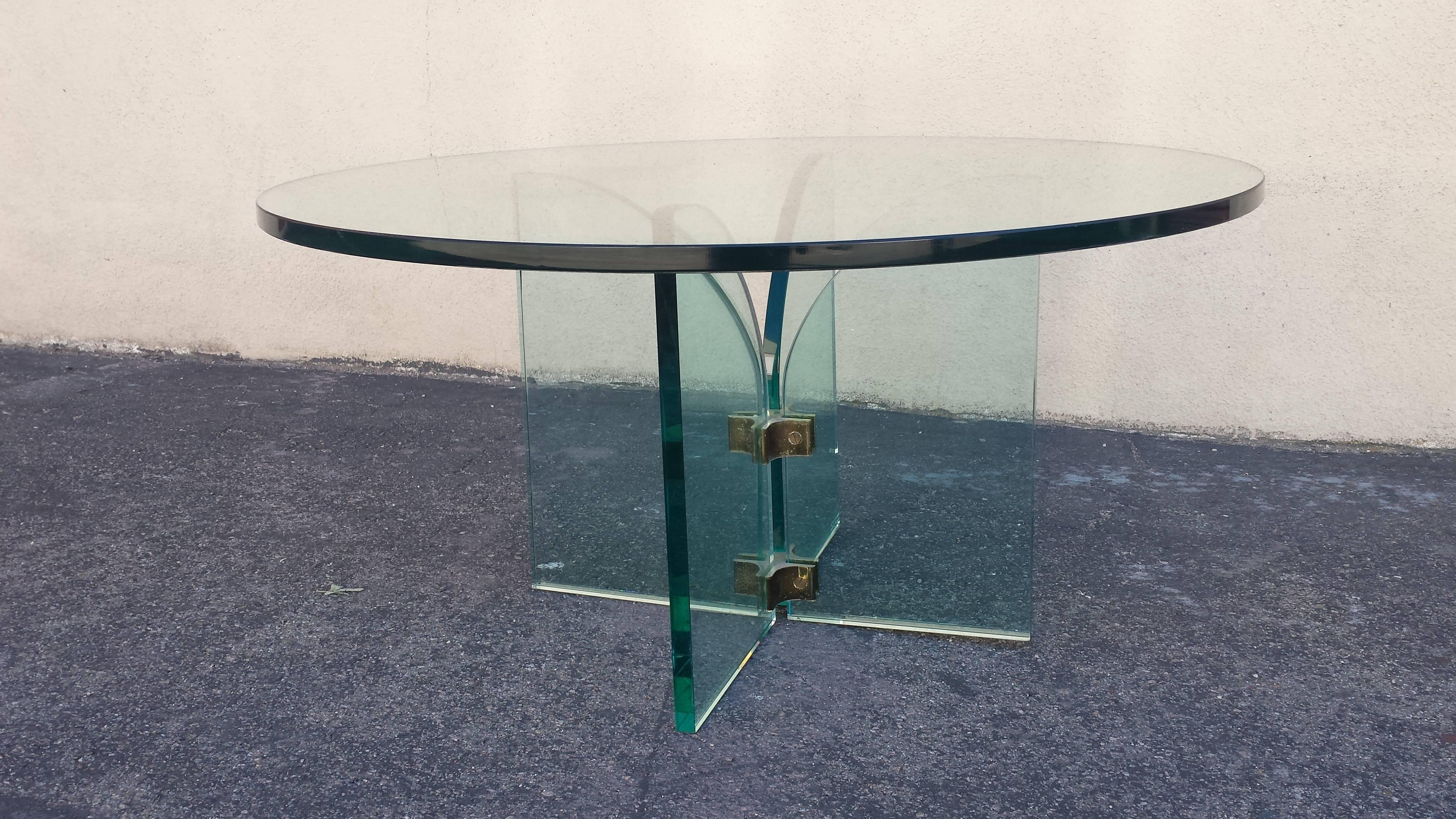 A  sleek round glass coffee or cocktail table in the mid century modern style. The glass is 3/4
