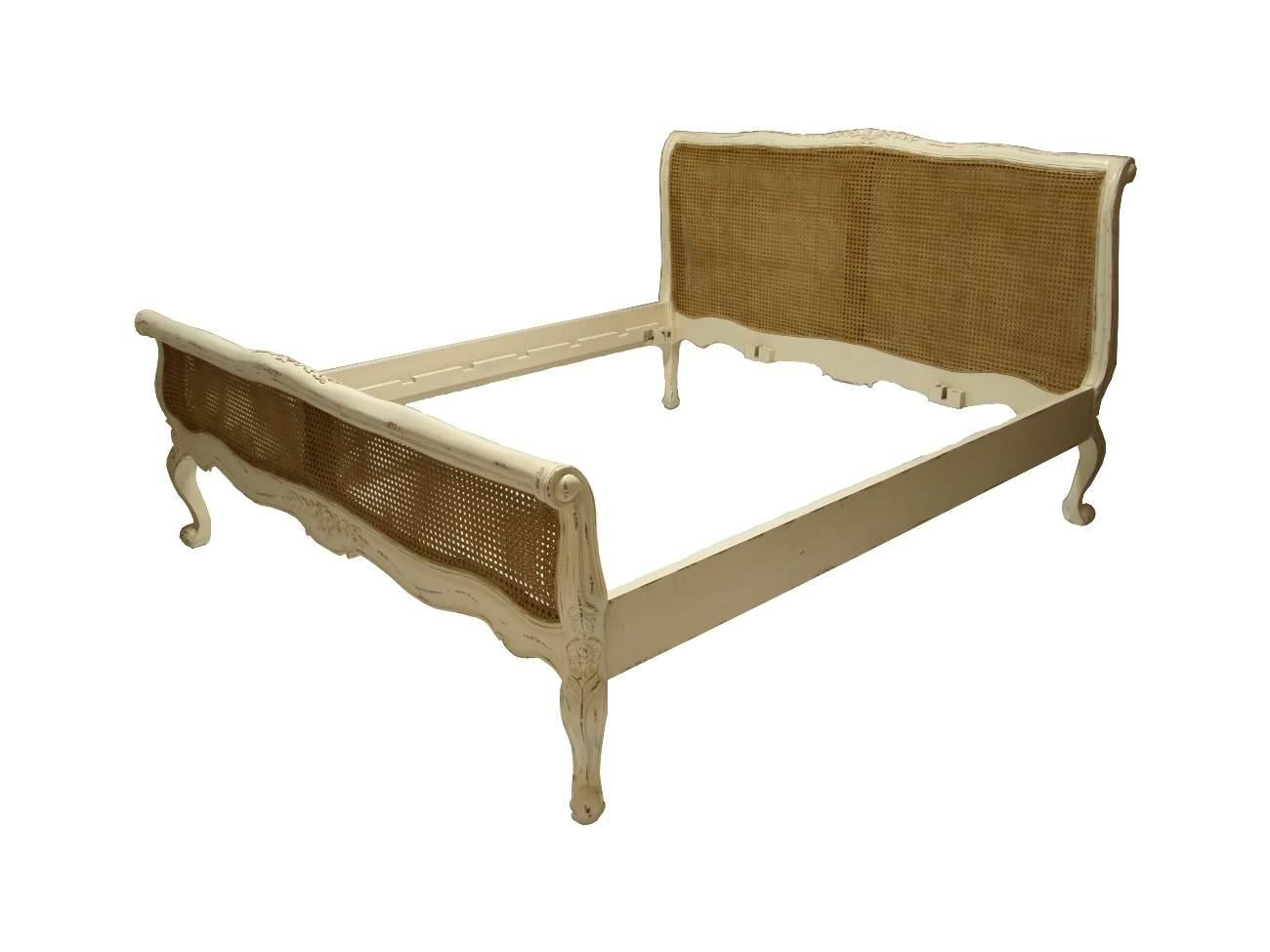 Beautiful French bed in the French Provincial chic style. The solid mahogany wooden frame is finished in light distressed cream finish. Natural cane insert on the head and foot board. Pretty floral handmade carvings shown.
This bed will fit a