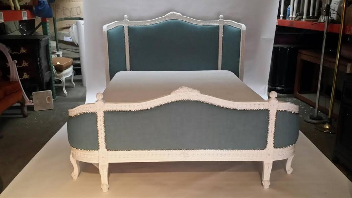 French XV style queen style bed frame. Newly upholstered in cotton blend fabric and finished in distressed white. A unique side rails with open storage.