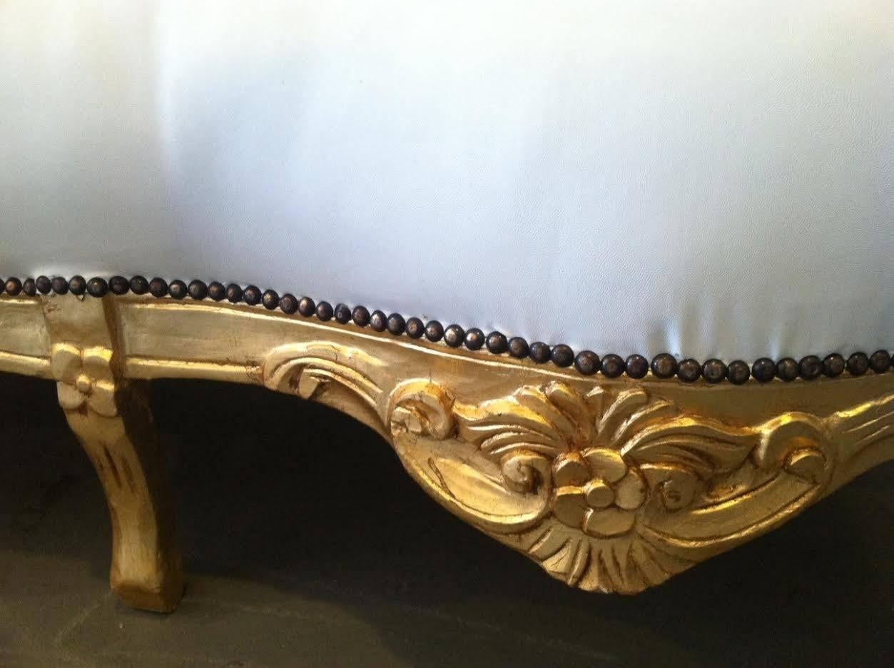 Beautiful sofa in the French Rococo Louis XV style. Newly covered in white faux leather. Carved frame in gold leaf finish. Nailheads shown.