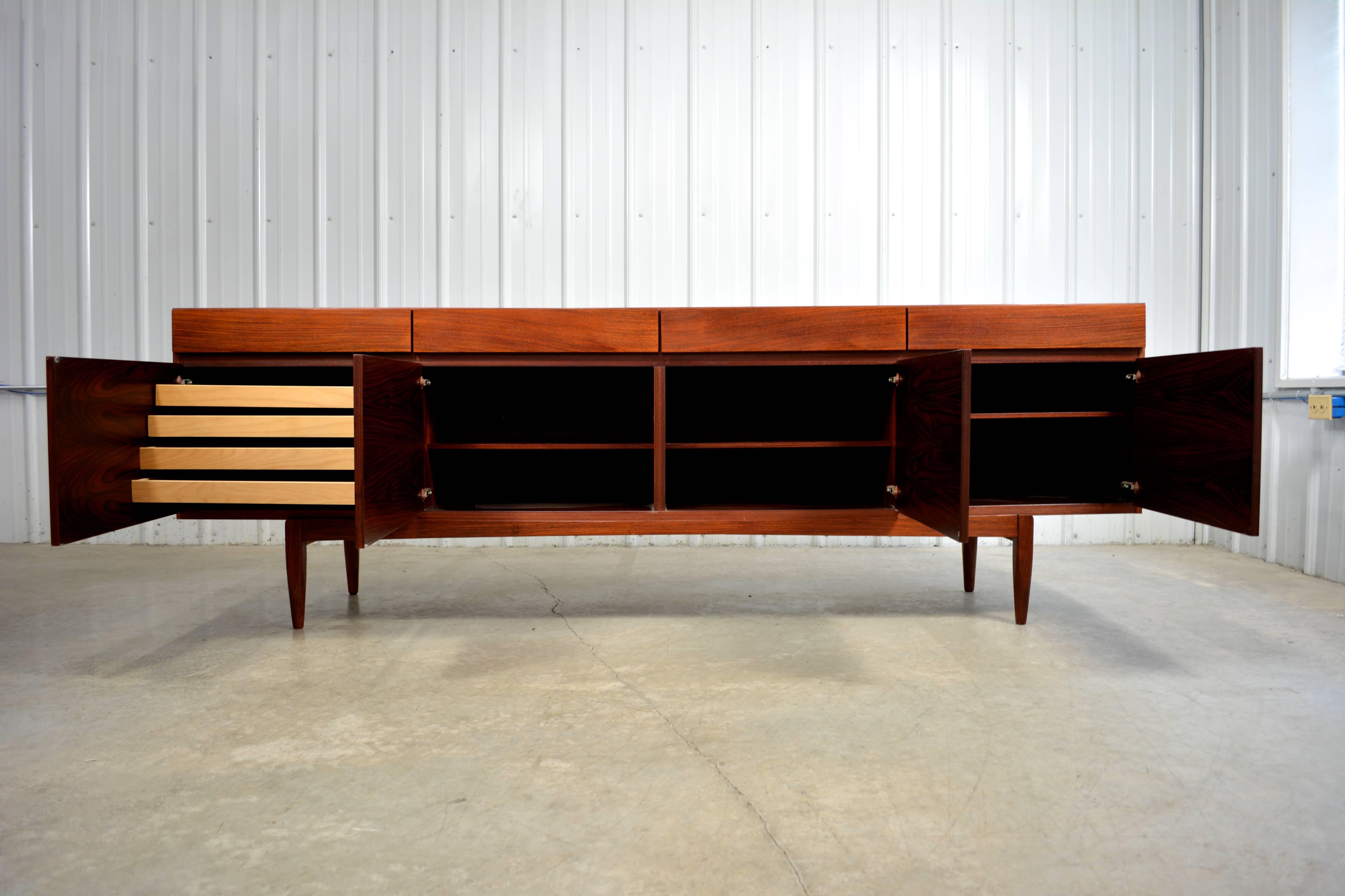 Rosewood credenza by Ib Kofod-Larsen for Faarup Mobelfabrik. Exceptional rosewood grain. Four doors open to reveal open storage with adjustable shelves and sliding, felt lined drawers. Above, there are four additional drawers.