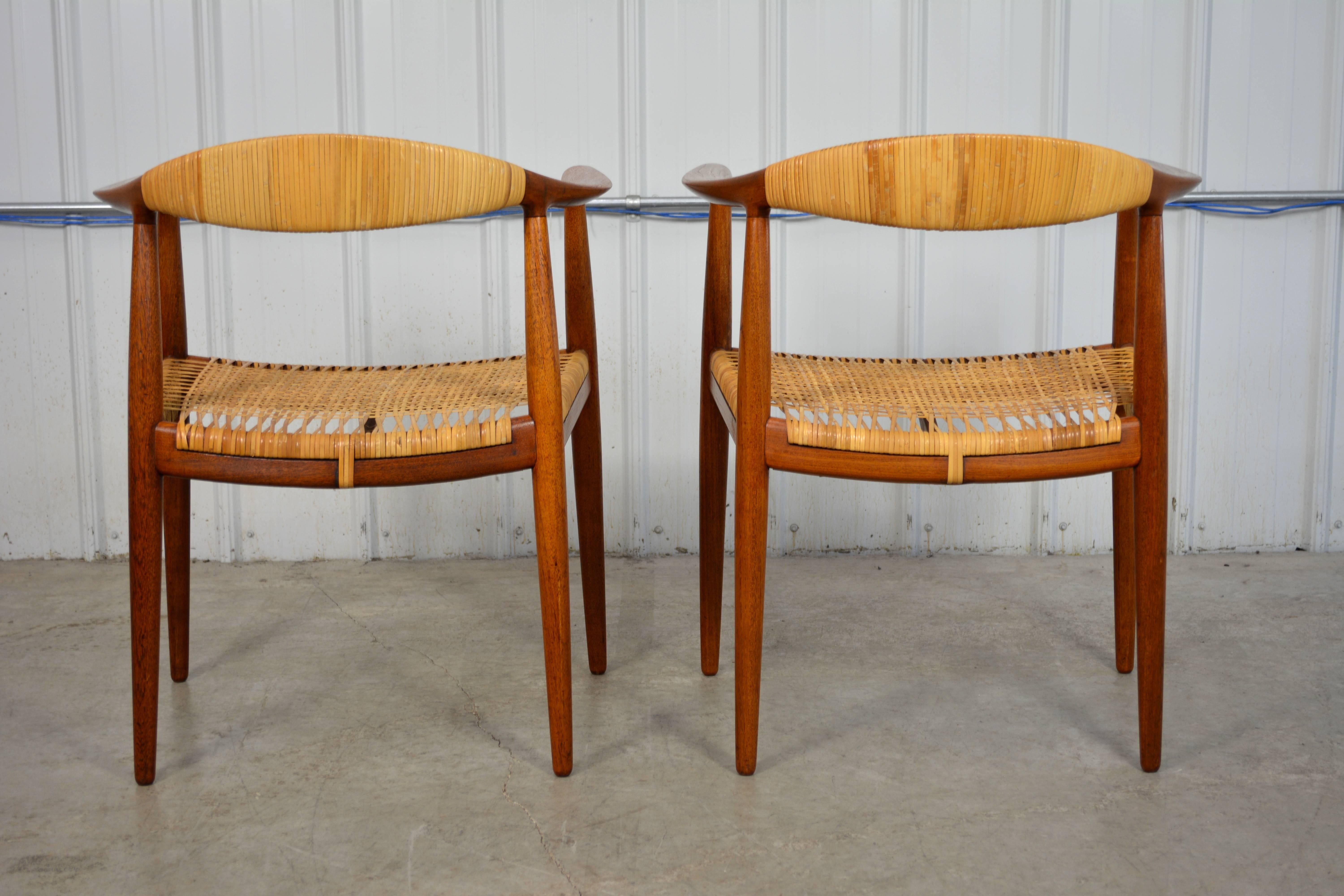 An early pair of "Round" chairs by Hans Wegner for Johannes Hansen in original condition. Solid teak frame with beautifully aged patina. Caned seats and cane wrapped backs. Two more matching chairs available.