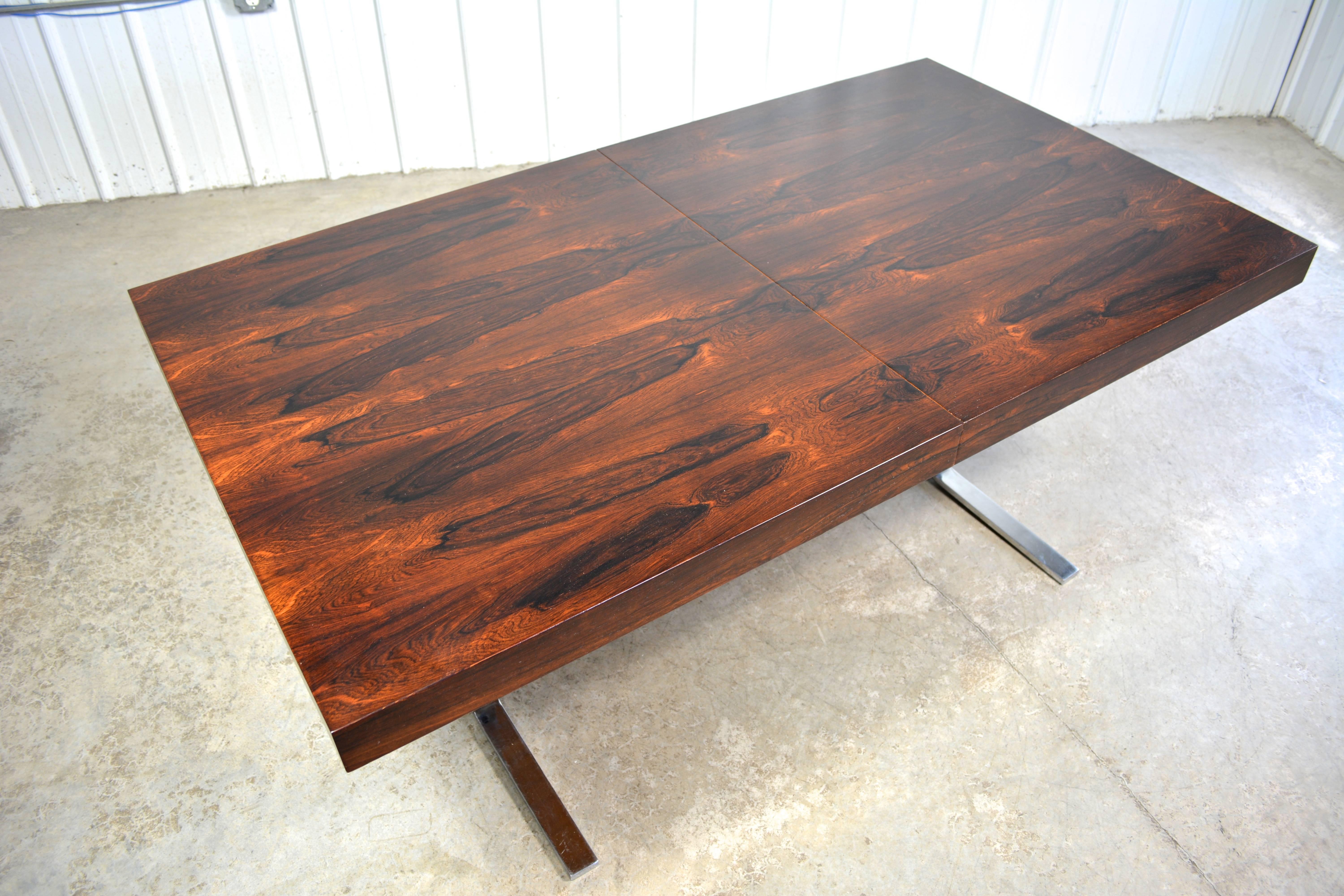 Dining table by Georg Petersens. Heavy chromed steel base. Tabletop has a vibrant rosewood grain. The 23.75" leaf stores under the tabletop.