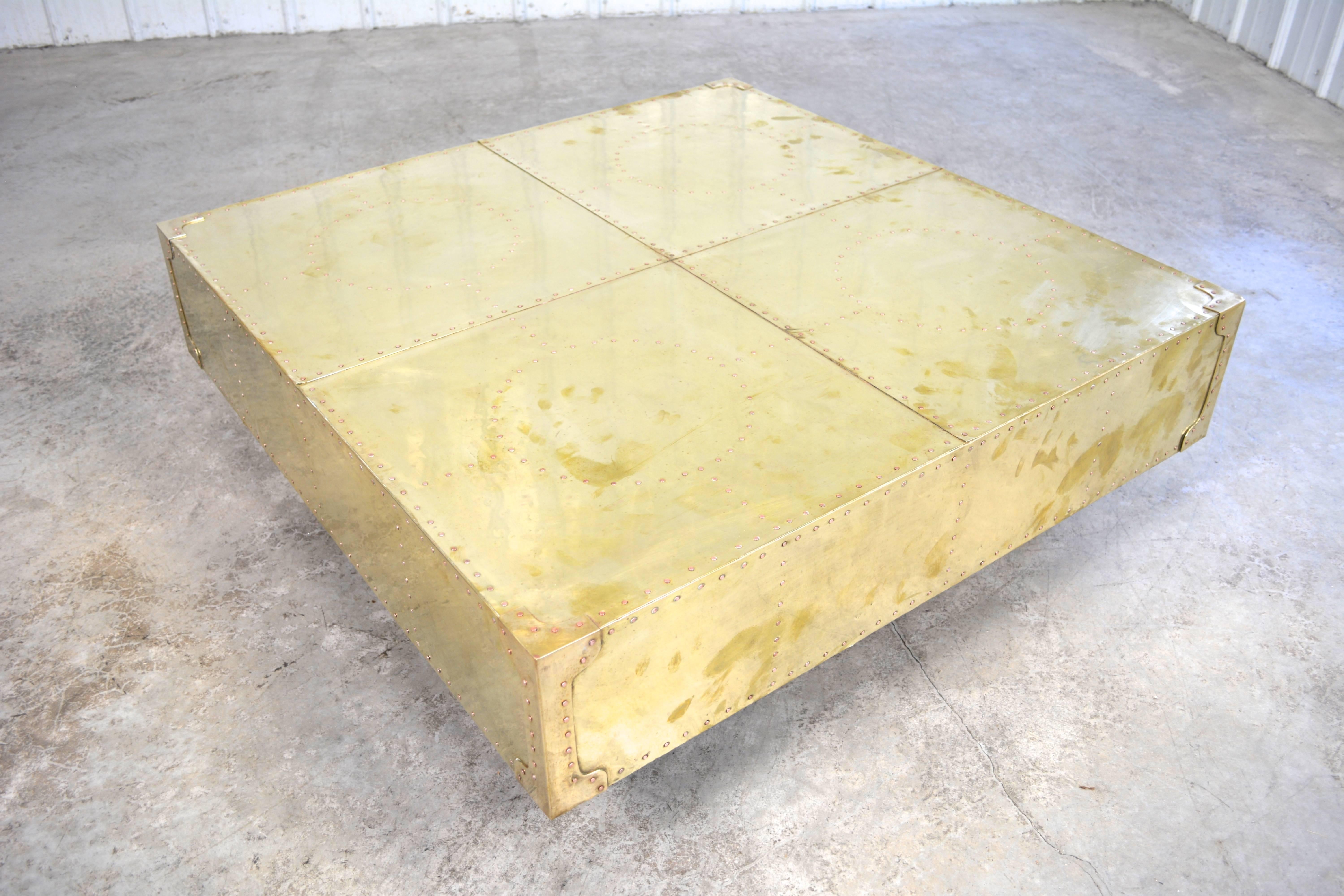 A gorgeous large-scale coffee table by Sarreid. Studded brass table sits on a walnut plinth base. Nicely aged patina present on the brass.