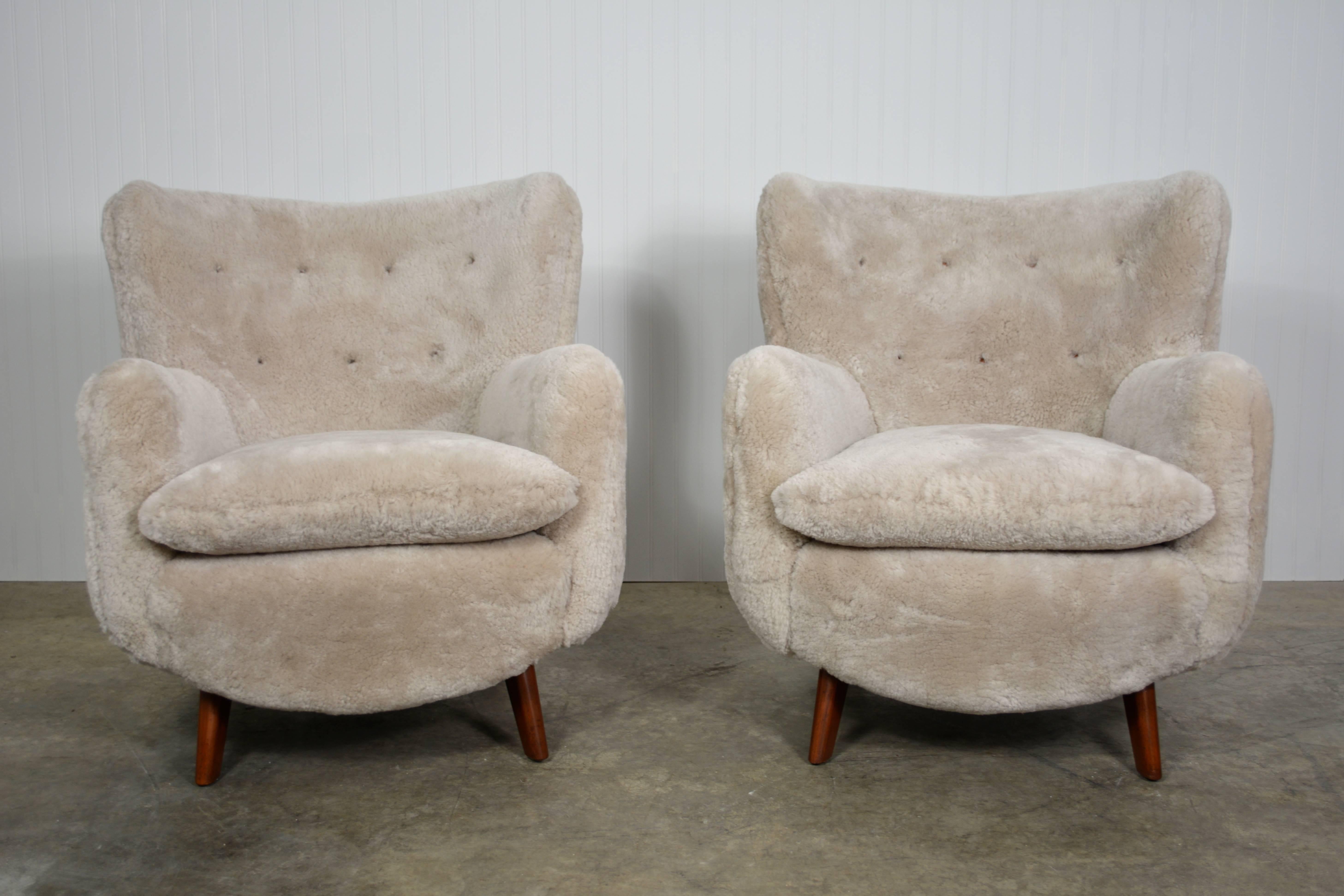 An exceptional pair of rare, early lounge chairs by George Nelson (circa 1948) completely restored in luxurious sheepskin. This pair also features leather button tufted backs. The flowing form of the chairs is a feature of early American and