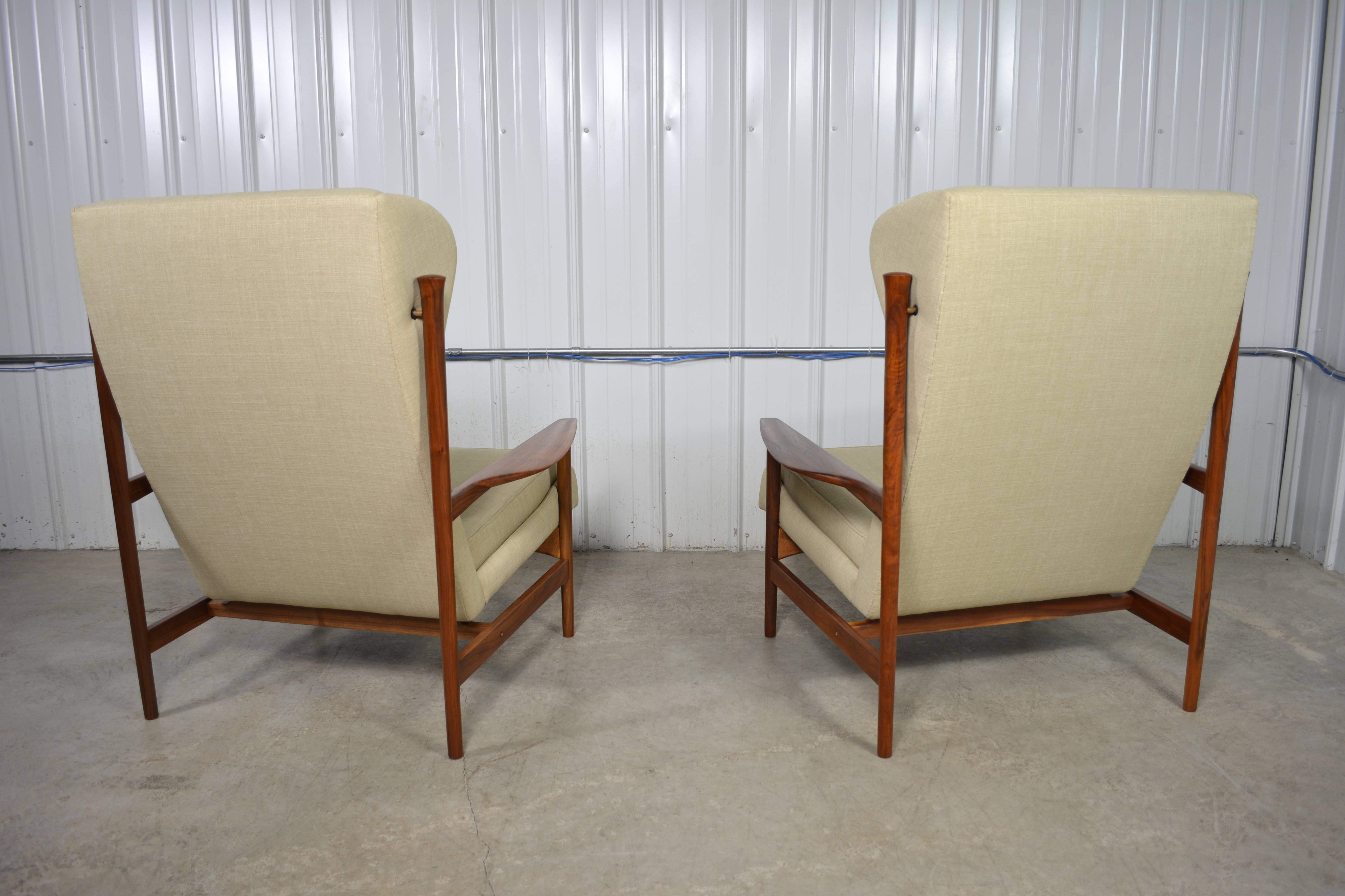 A rare pair of of wingback lounge chairs designed by Ib Kofod-Larsen for Selig. These chairs are generously proportioned. Beautiful solid walnut frames. Newly restored.