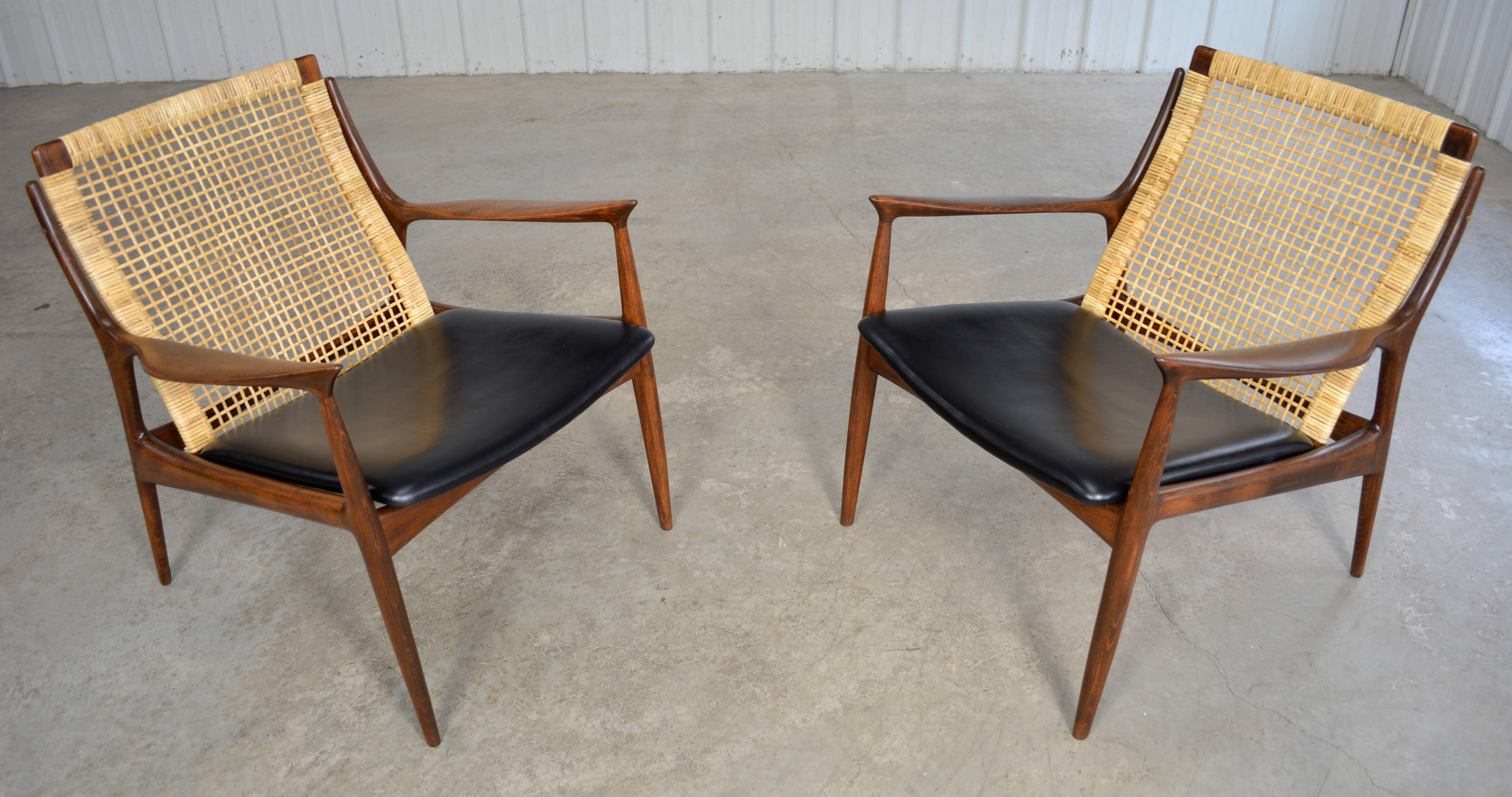 Pair of sculptural walnut lounge chairs with caned backs by Ib Kofod-Larsen. They are newly restored and in perfect condition.