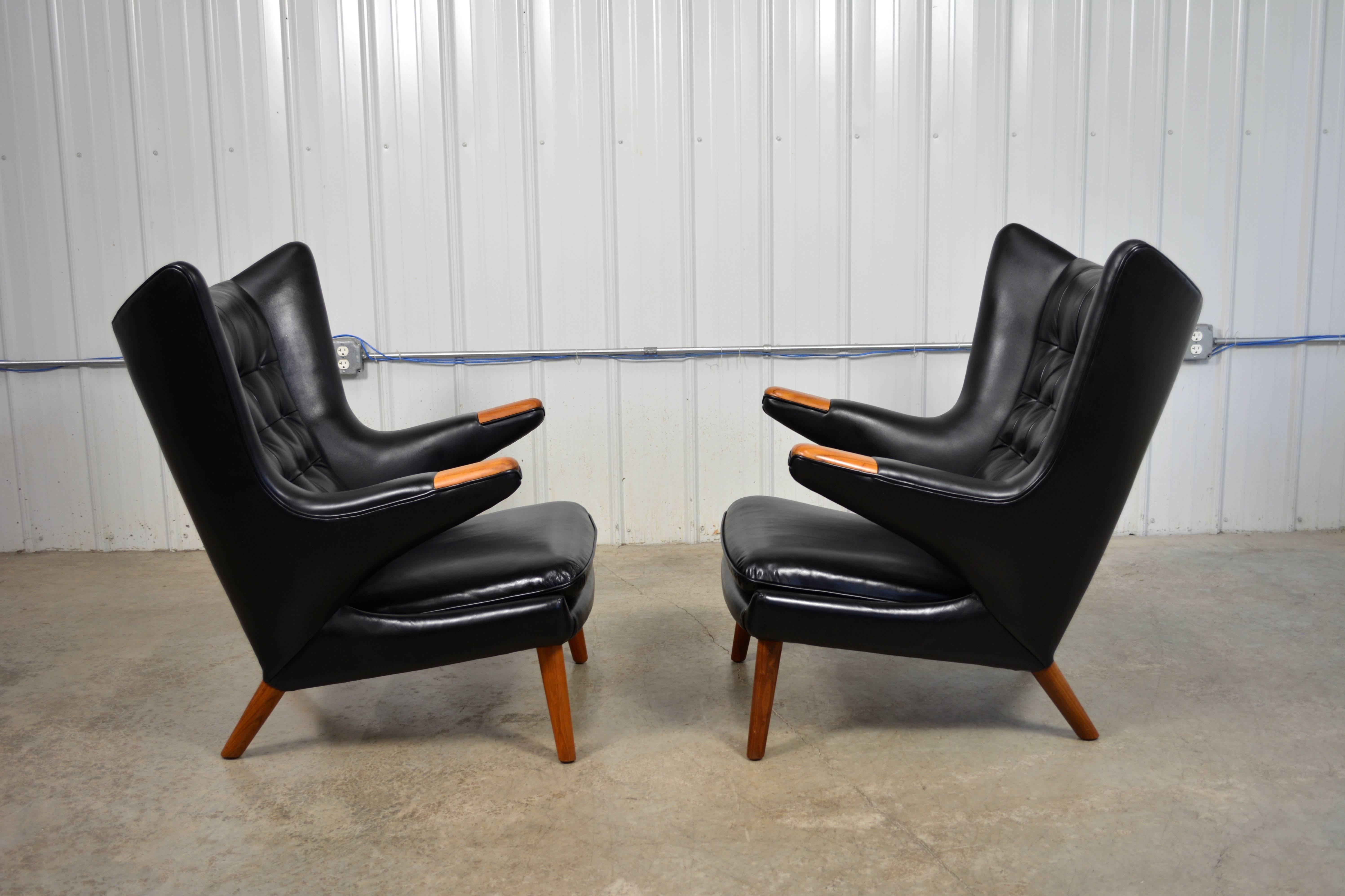 A pair of Hans Wegner "Papa Bear" chairs designed in 1951 for A.P. Stolen. Both chairs are labeled. Black leather upholstery. Teak legs and paws. 