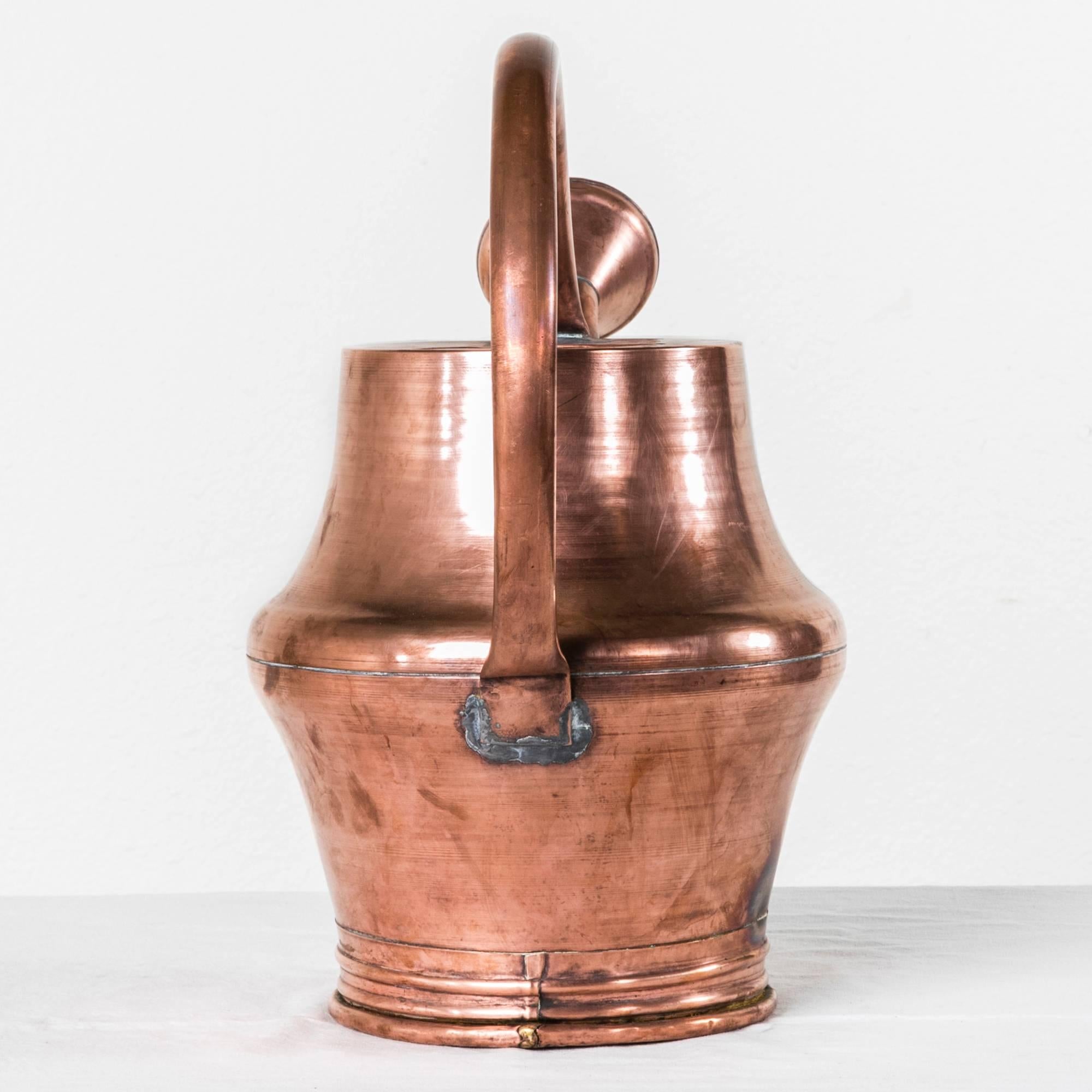 This unusually large-scale copper watering can features a unique large circular handle. Created in late 19th century France, this piece will make a stunning decorative piece for copper and gardening lovers.