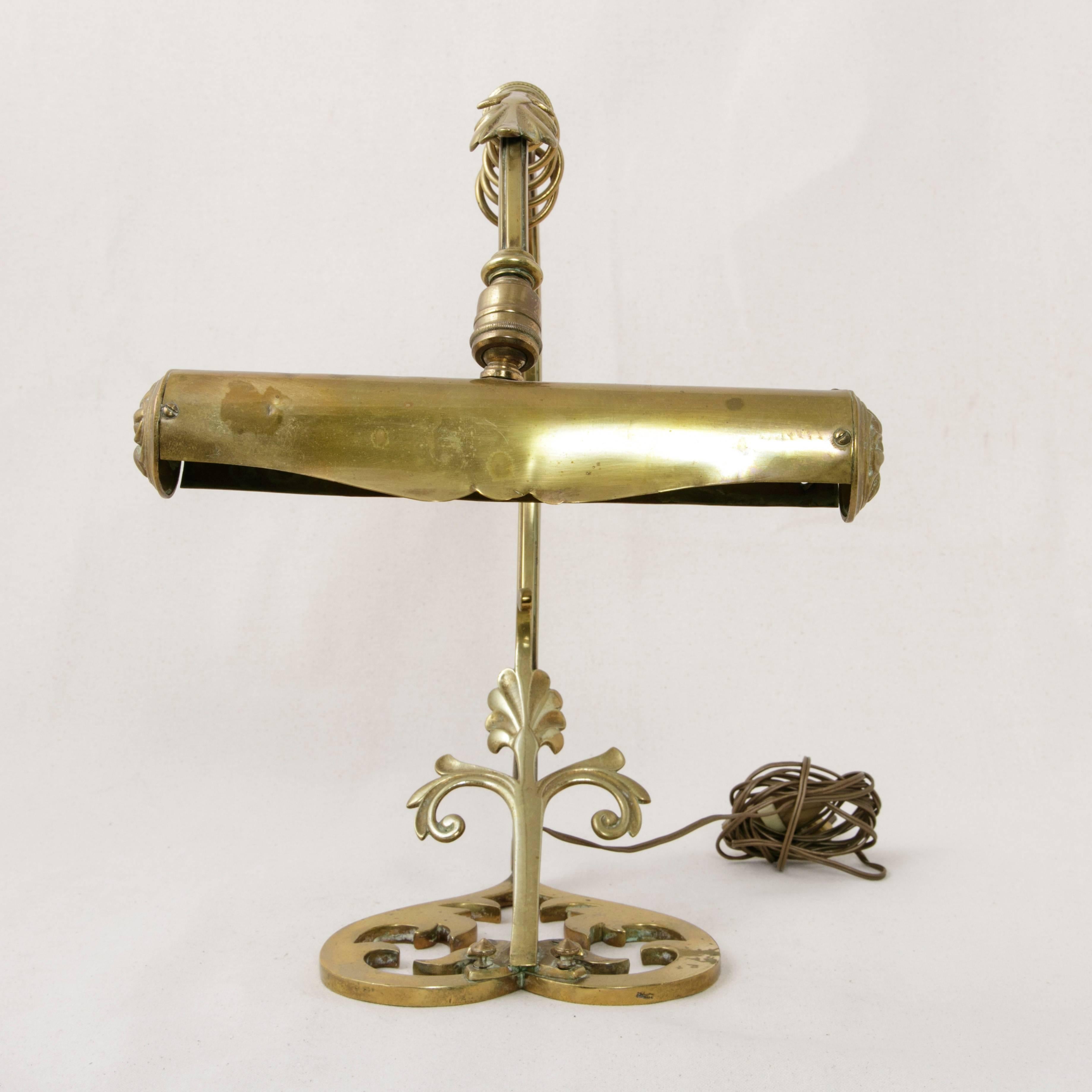 A rare find, this Art Nouveau period bronze lamp was created to light music at a piano, but also makes a lovely formal desk lamp. A scrollwork and leaf motif is carried across its base and up its curved arm. The design in the bronzework base stands
