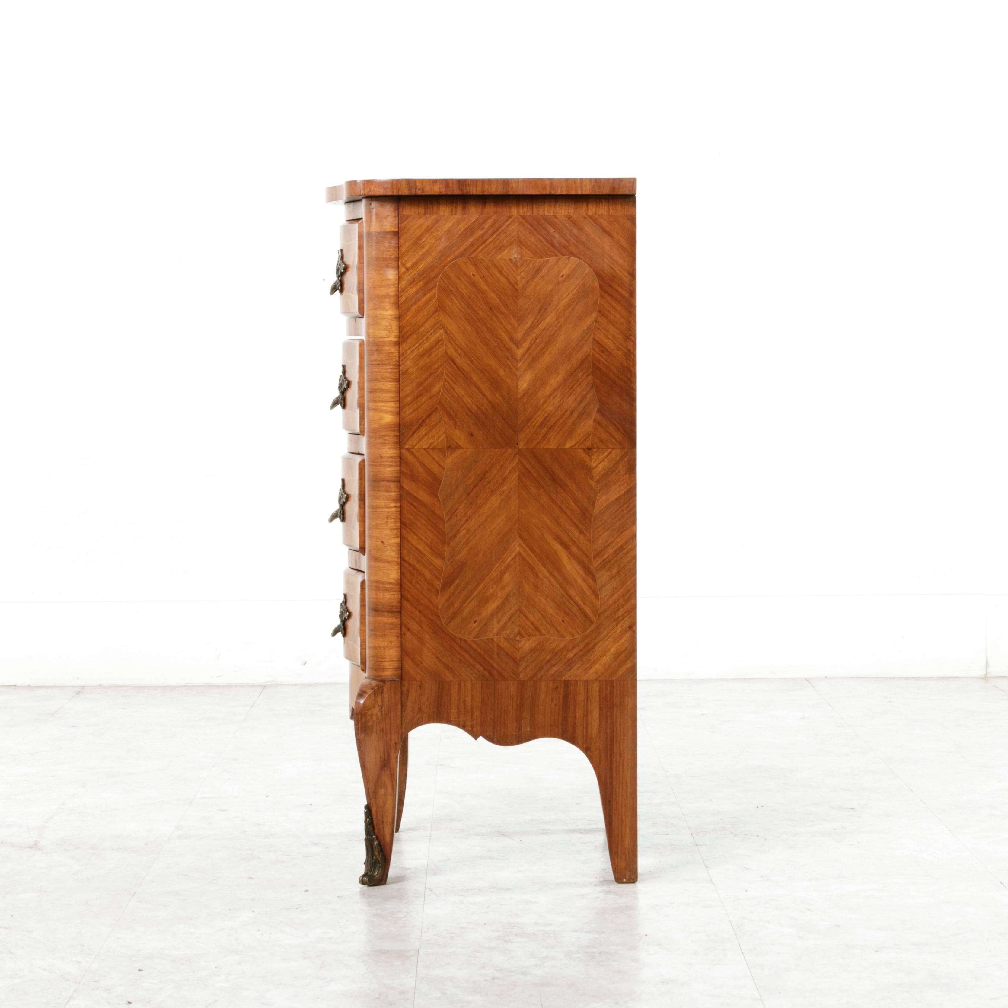 This intricately inlaid small-scale Louis XV style inlaid chest or nightstand was originally designed to hold lingerie and jewelry. Its four drawer body has a serpentine front which smoothly transitions to cabriole legs ending in bronze sabots. With
