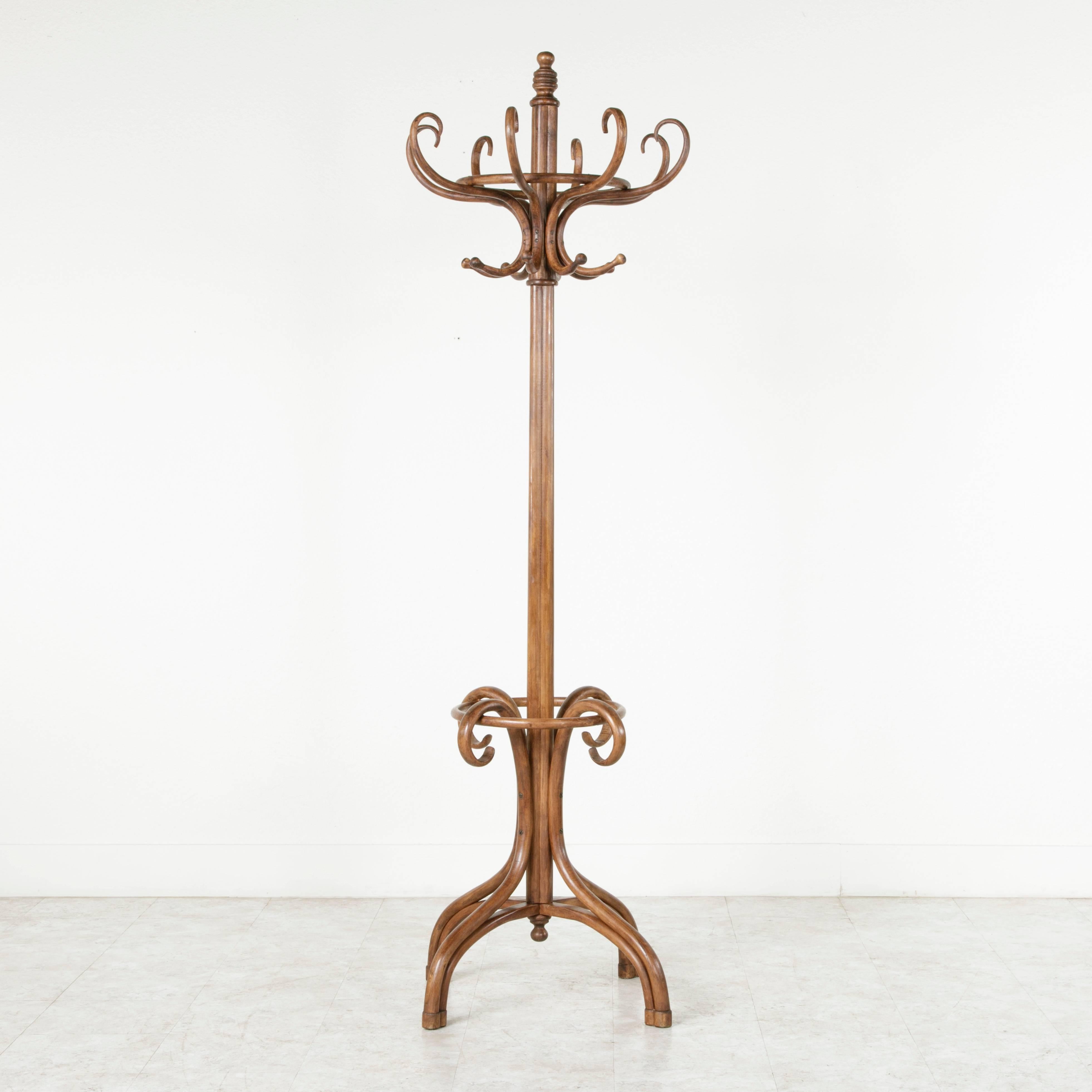 This classic Thonet style hat and coat rack or hall tree is made of richly finished bent beechwood. It features sixteen hat and coat hooks and an umbrella holder below.  A familiar fixture in the turn-of-the-century French bistro, this piece will