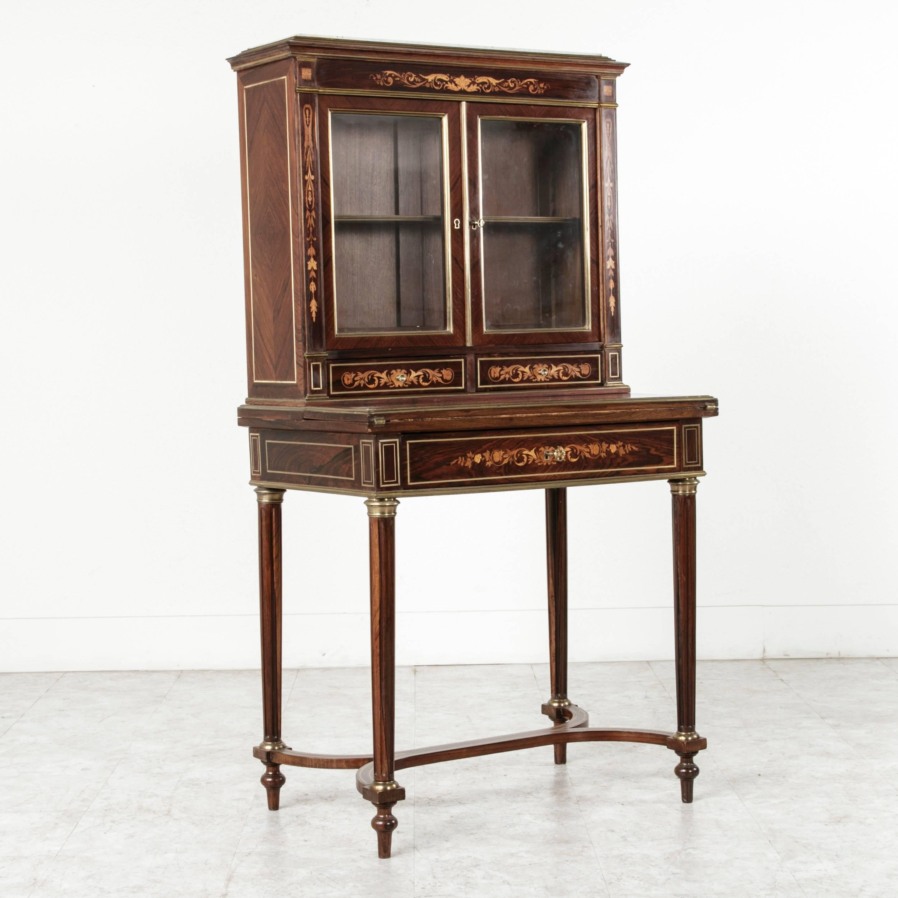 This exquisite French Bonheur Du Jour, or ‘daytime delight’ is impeccably inlaid with mahogany, rosewood, and lemonwood. Finished precisely with bronze mounts and banding, this piece is a writing desk and vitrine. The fold out writing surface, which