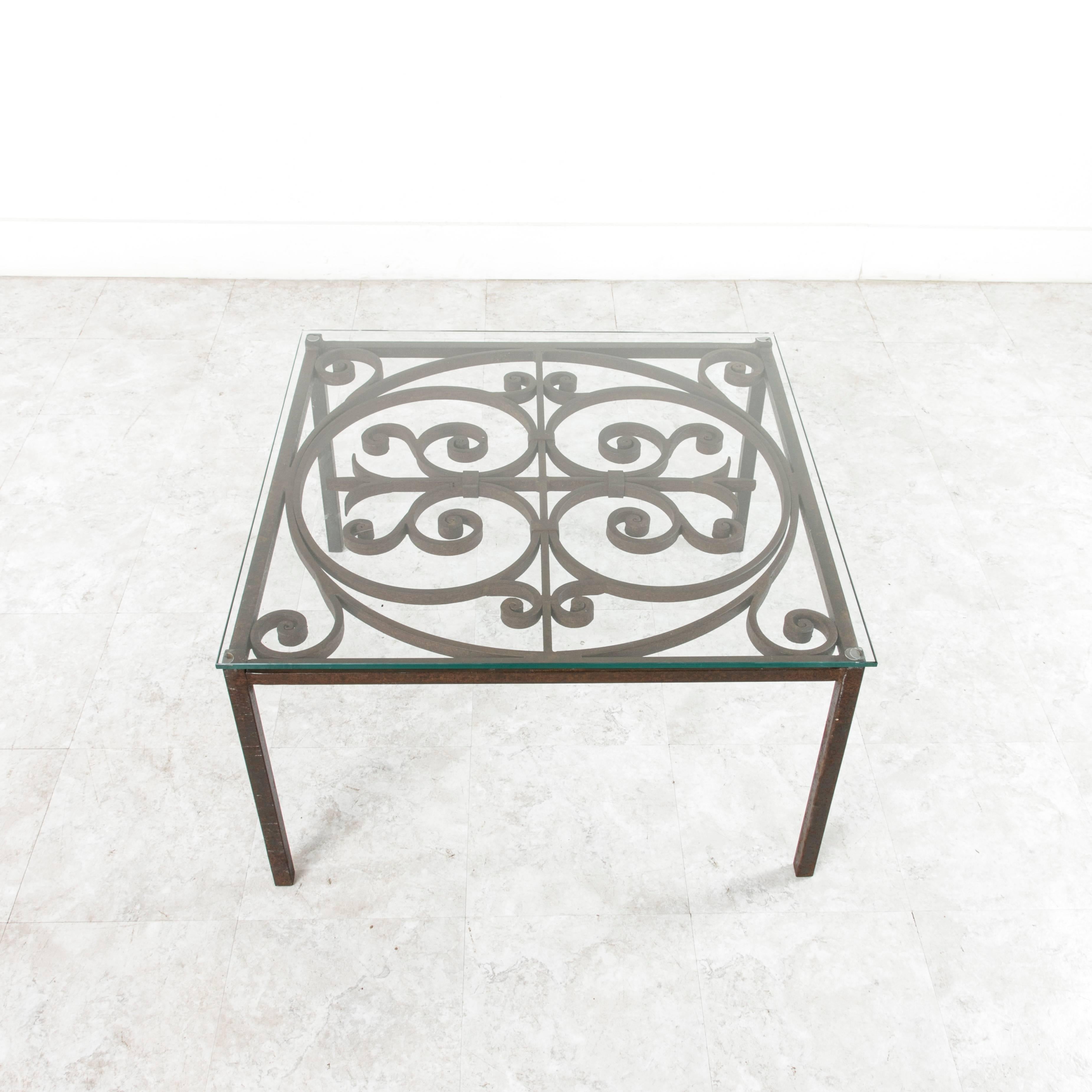 Created by artisans during the late 19th century in France, this hand-forged iron coffee table would function well for indoor or outdoor conversation spaces. The top is new 3/8 inch glass.
 