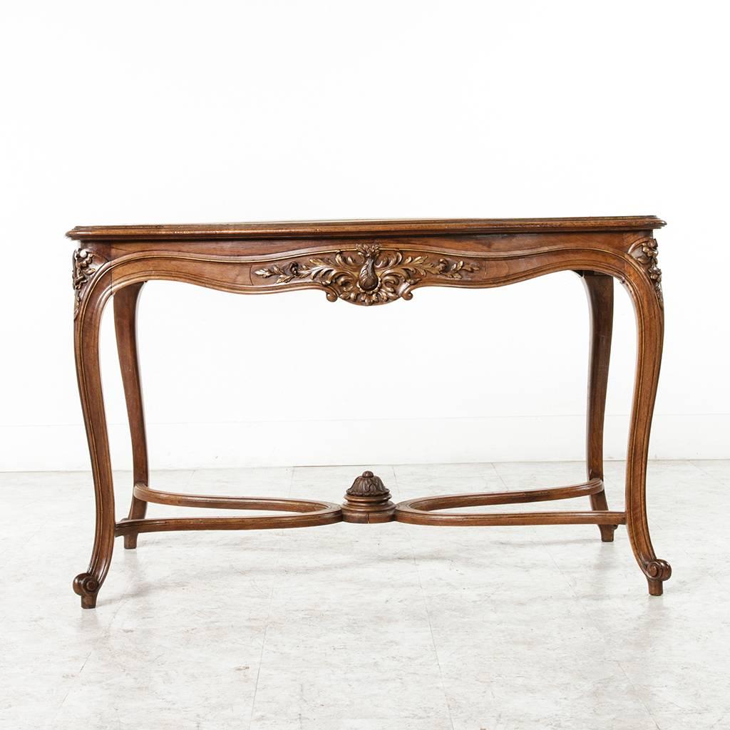 This finely detailed Louis XV style table de milieu or center table could function as a console, desk, or side table as well. Constructed of solid walnut with intricate deep relief carvings of acanthus and flowers on all four sides of its apron,